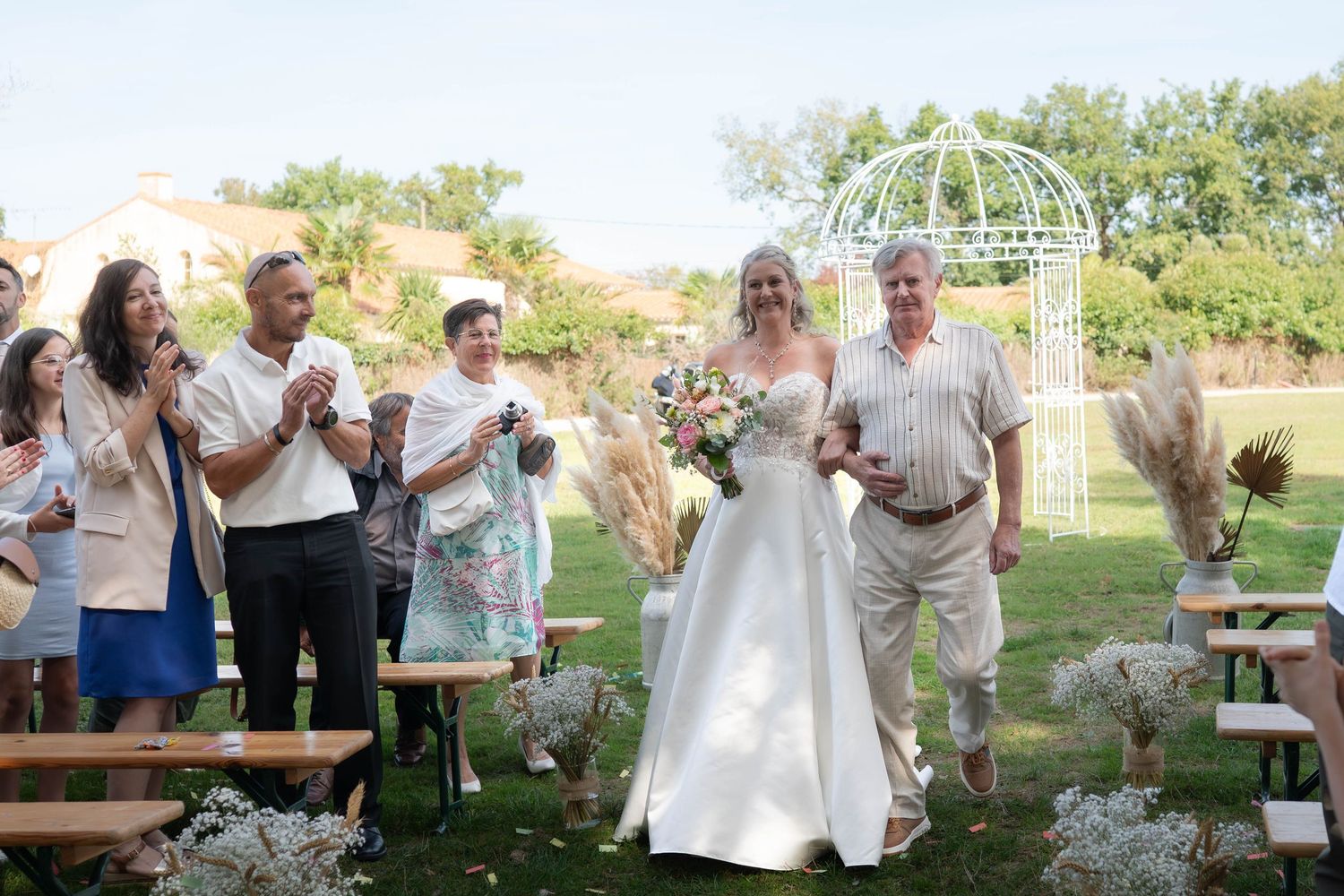 Outdoor wedding celebration with guests dancing and mingling in a garden setting during golden hour.