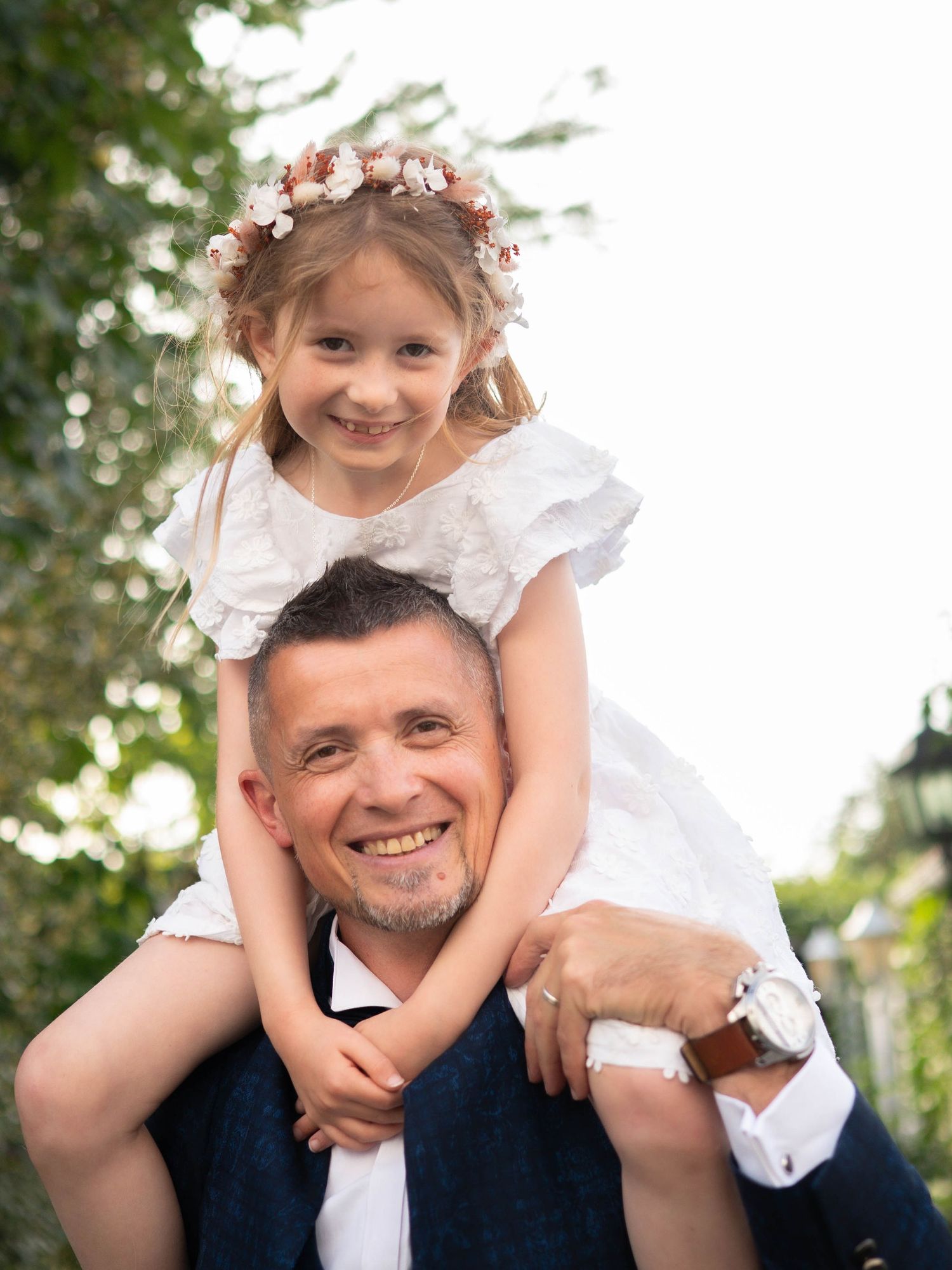 A sweet outdoor portrait showing a tender moment between two people wearing white and navy formal attire.