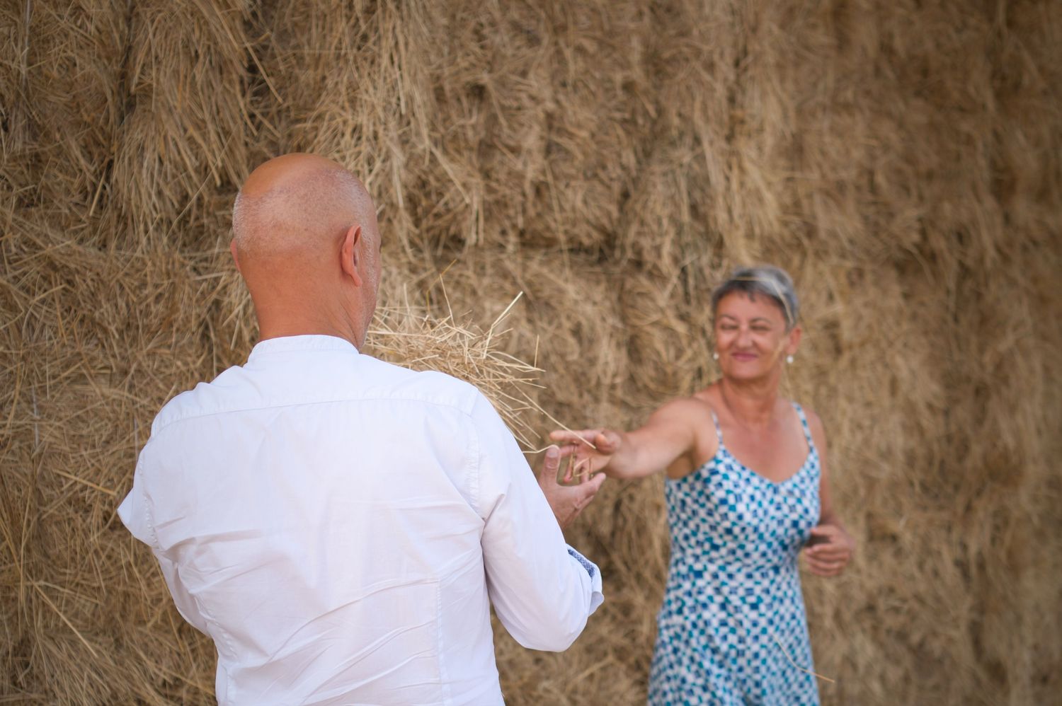Couple lying in tall grass on a sunny day sharing an intimate moment together.