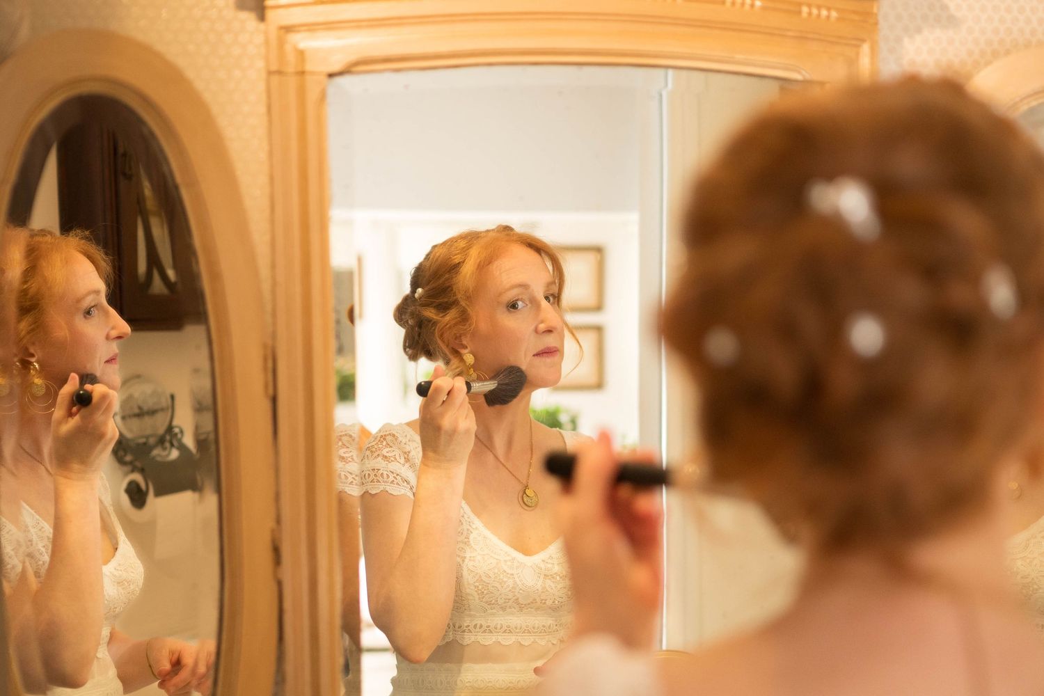 Ornate gold mirror reflecting preparation moments in elegant room setting.