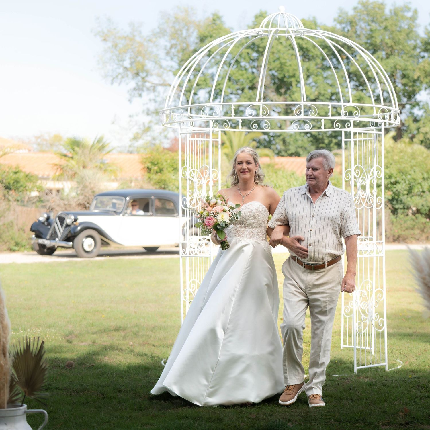 Couple dancing and twirling in an outdoor garden setting with white decorative arbors.