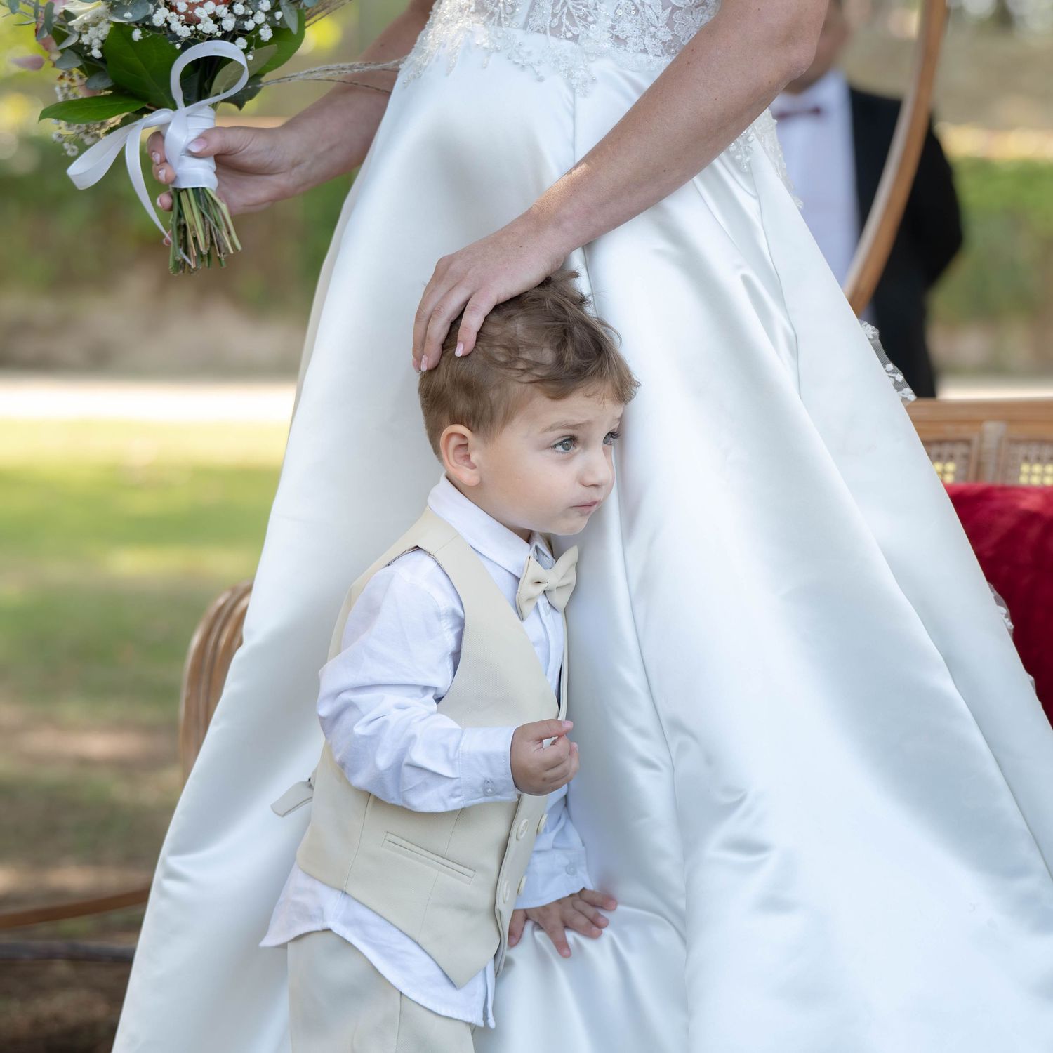 A series of wedding photos showing a child in white formal attire interacting with a bride's white dress.