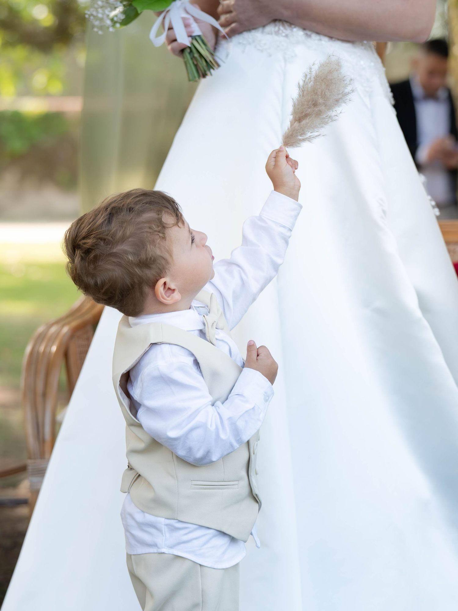 A touching wedding moment shows a small child in white being held against a wedding dress.