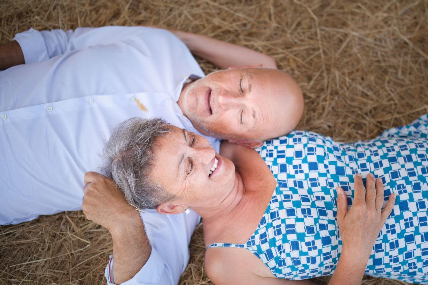 Person resting on hay bales wearing a blue and white patterned outfit.