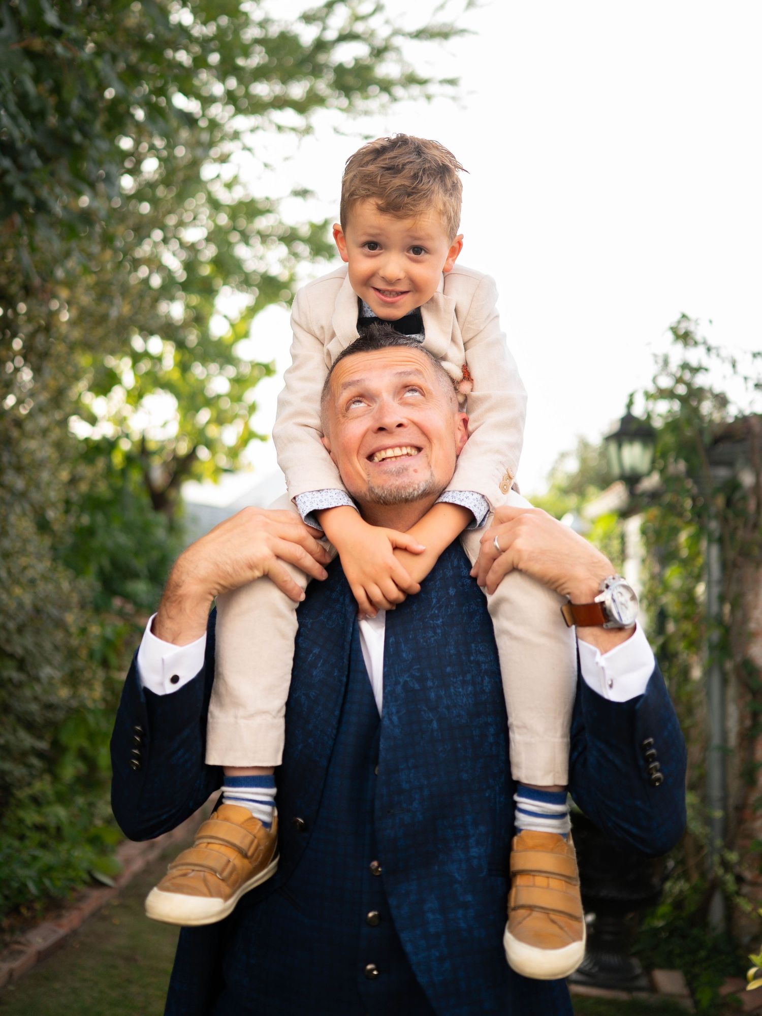 A playful outdoor portrait showing a parent and child having fun together in a natural garden setting.