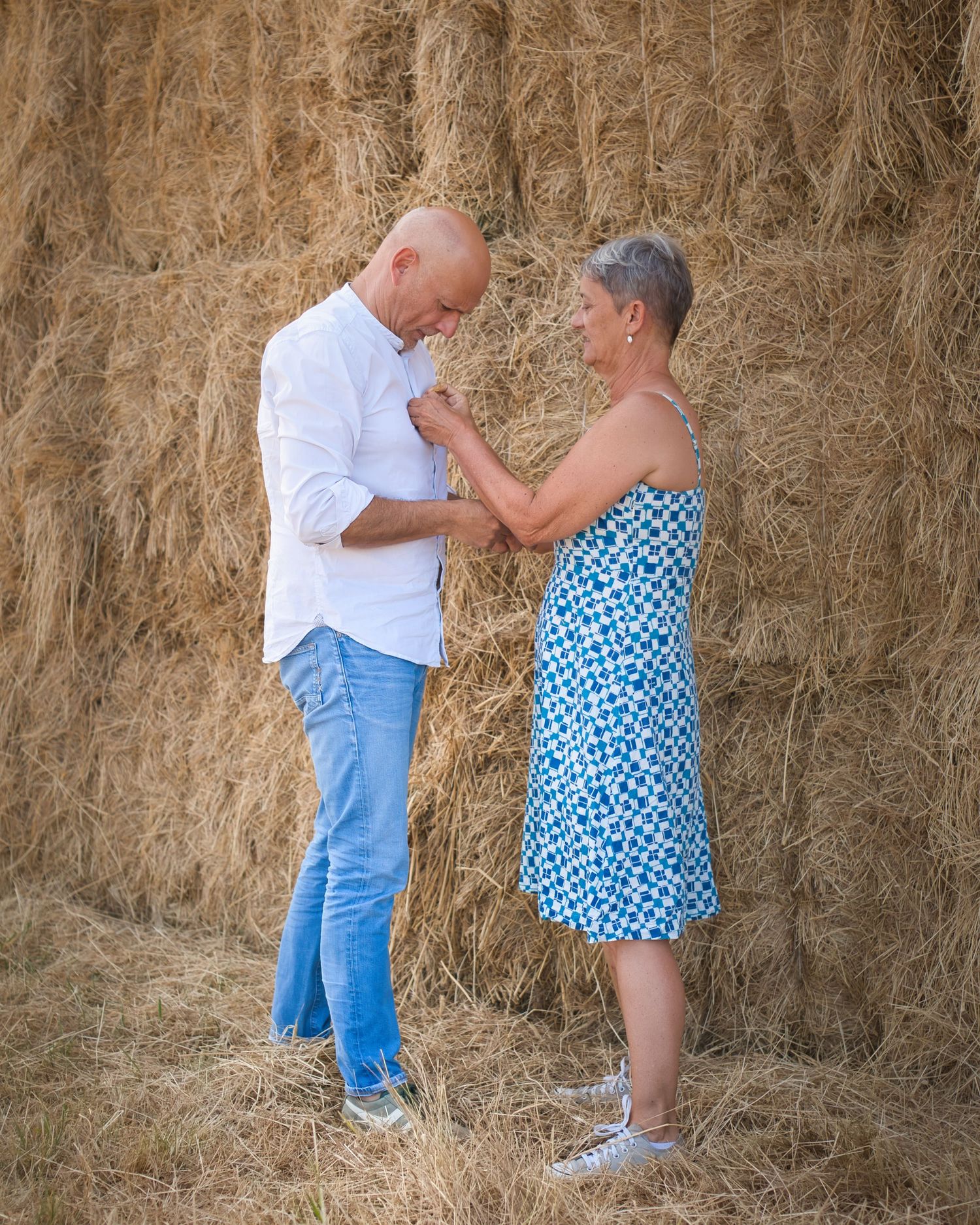 Couple sharing romantic dance moment by rustic hay bales in countryside setting.