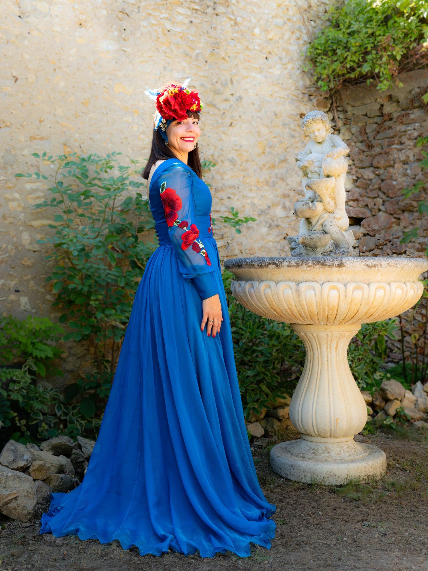Long flowing blue dress photographed near classical garden fountain.