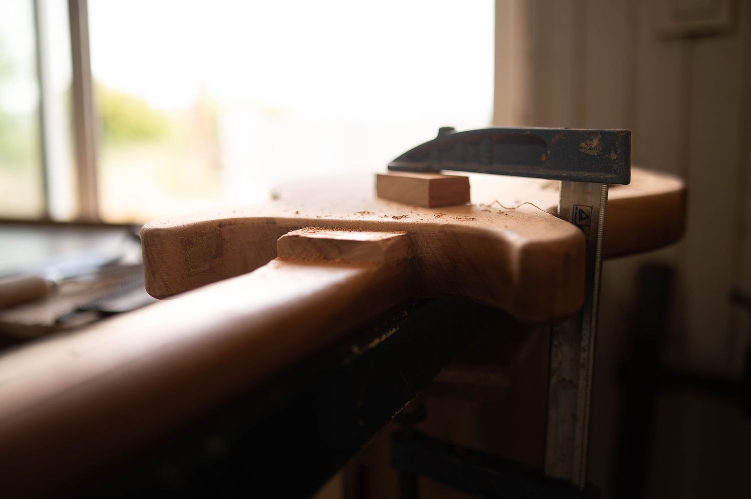 Soft focus view of guitar maintenance work being performed in natural lighting.