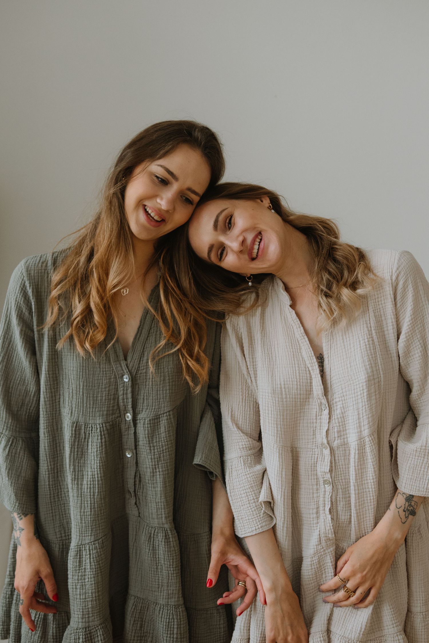 Two friends in flowing dresses sharing tender moment.