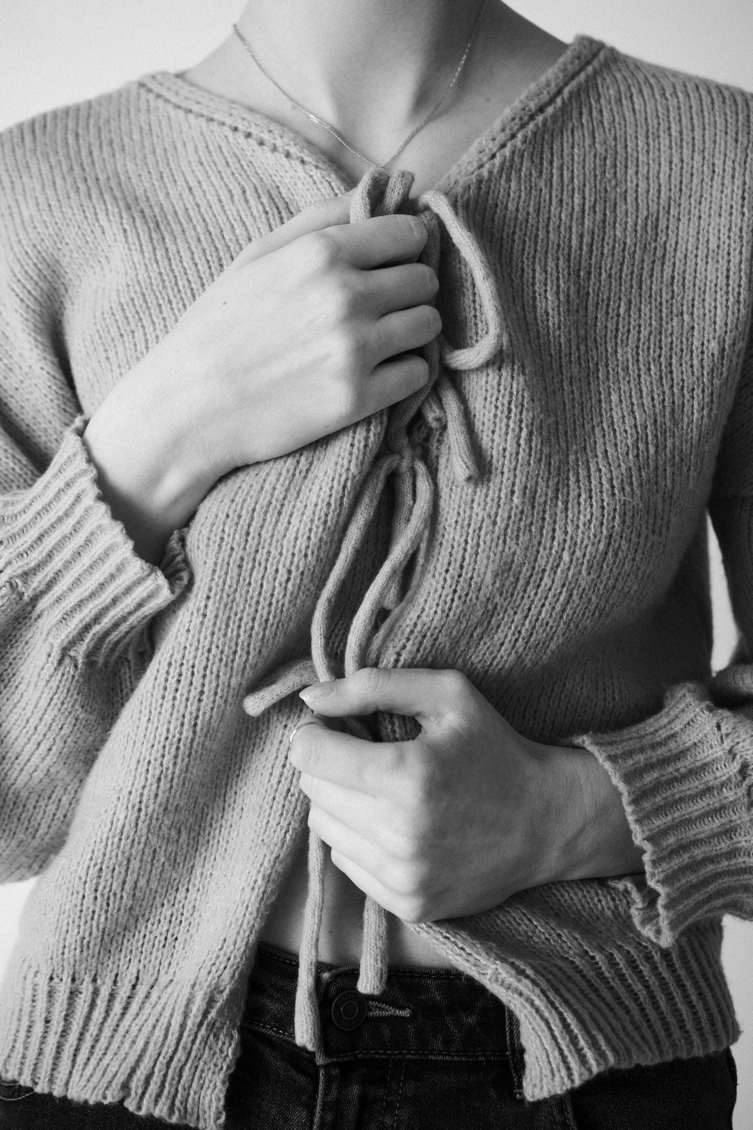 Close-up shots of hands grasping a gray knit sweater in various poses.