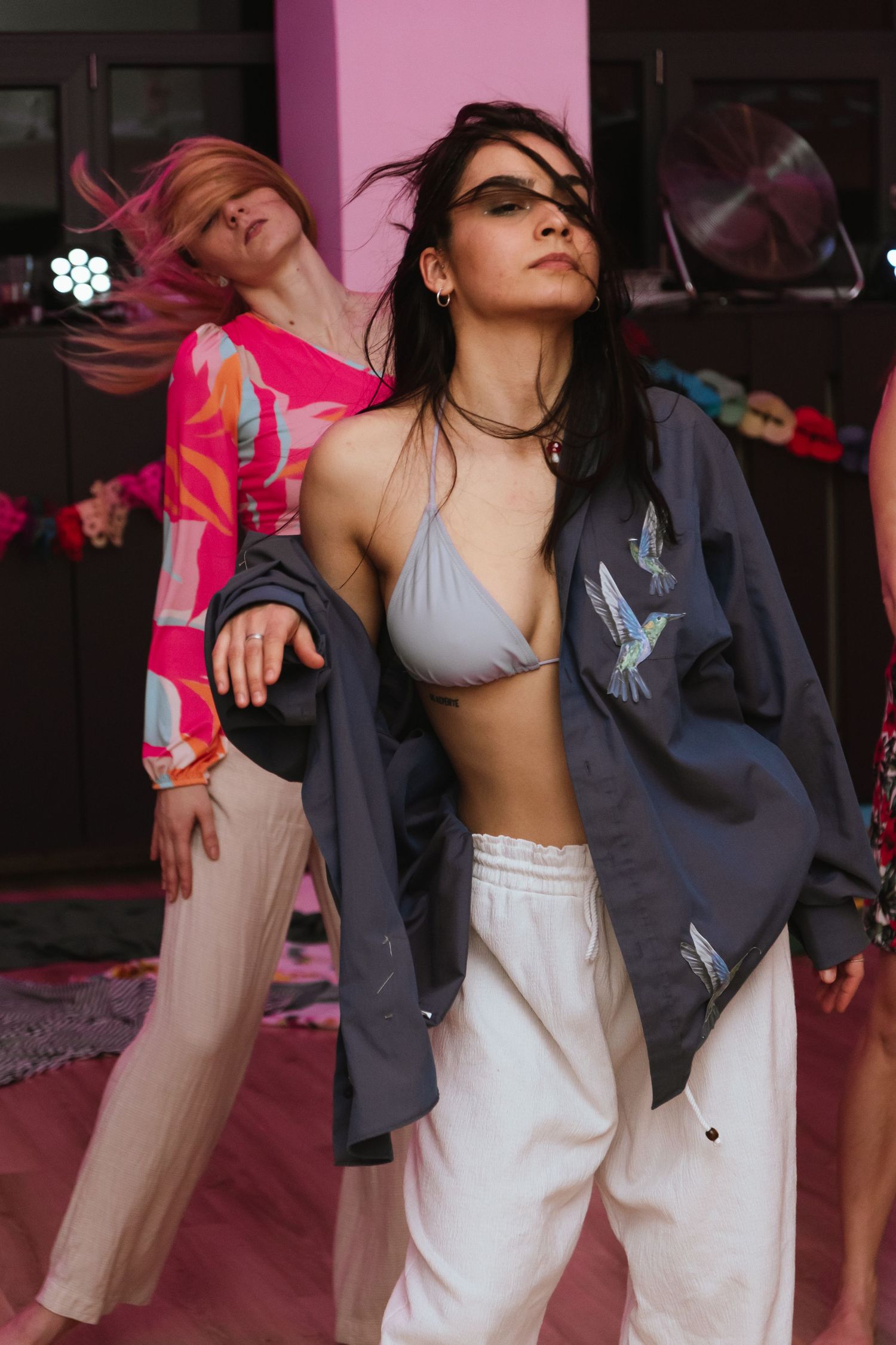 Fashion editorial with models in contrasting casual and athletic wear against pink backdrop.
