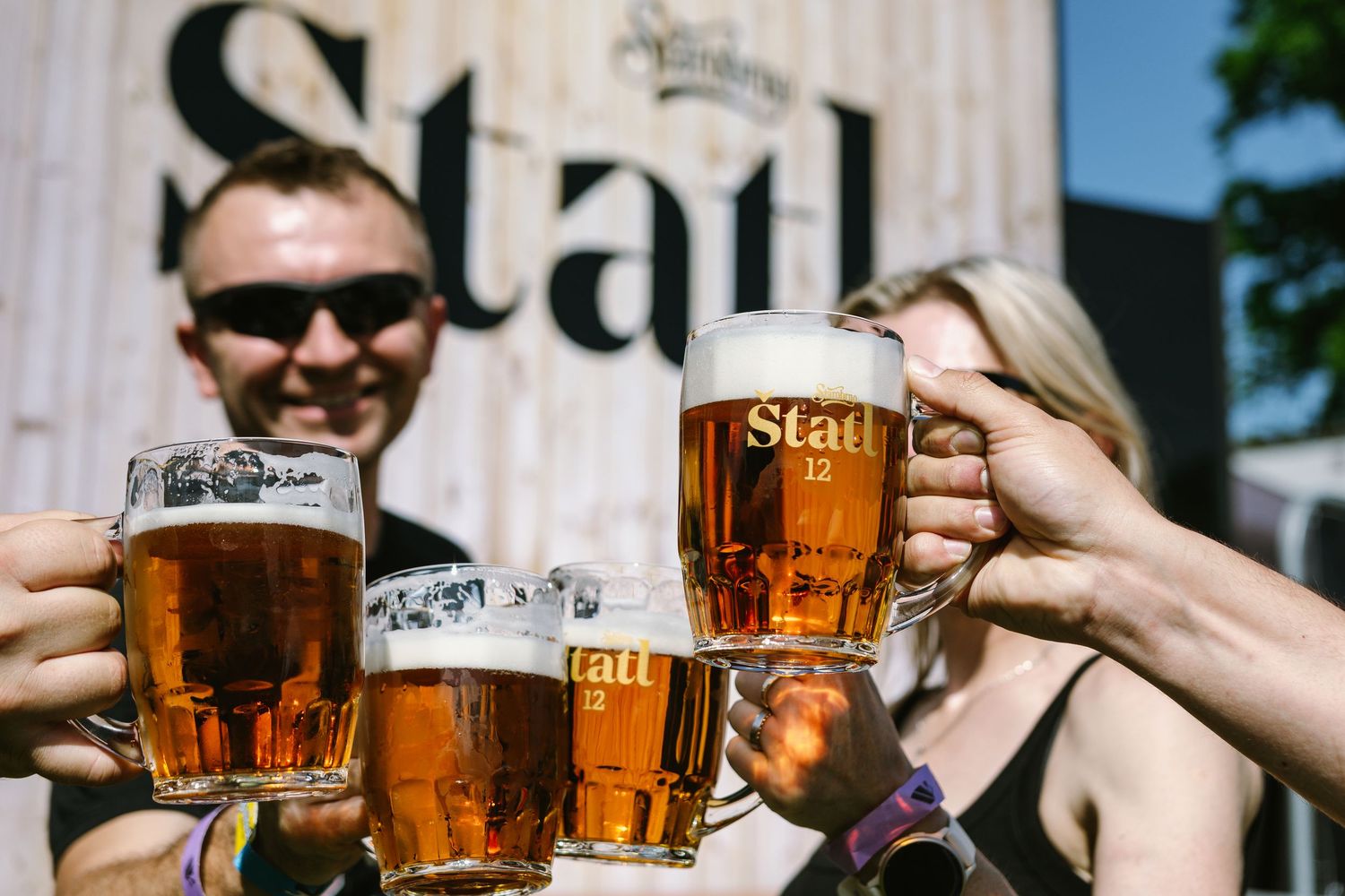 Multiple glasses of golden beer being toasted together in celebration.