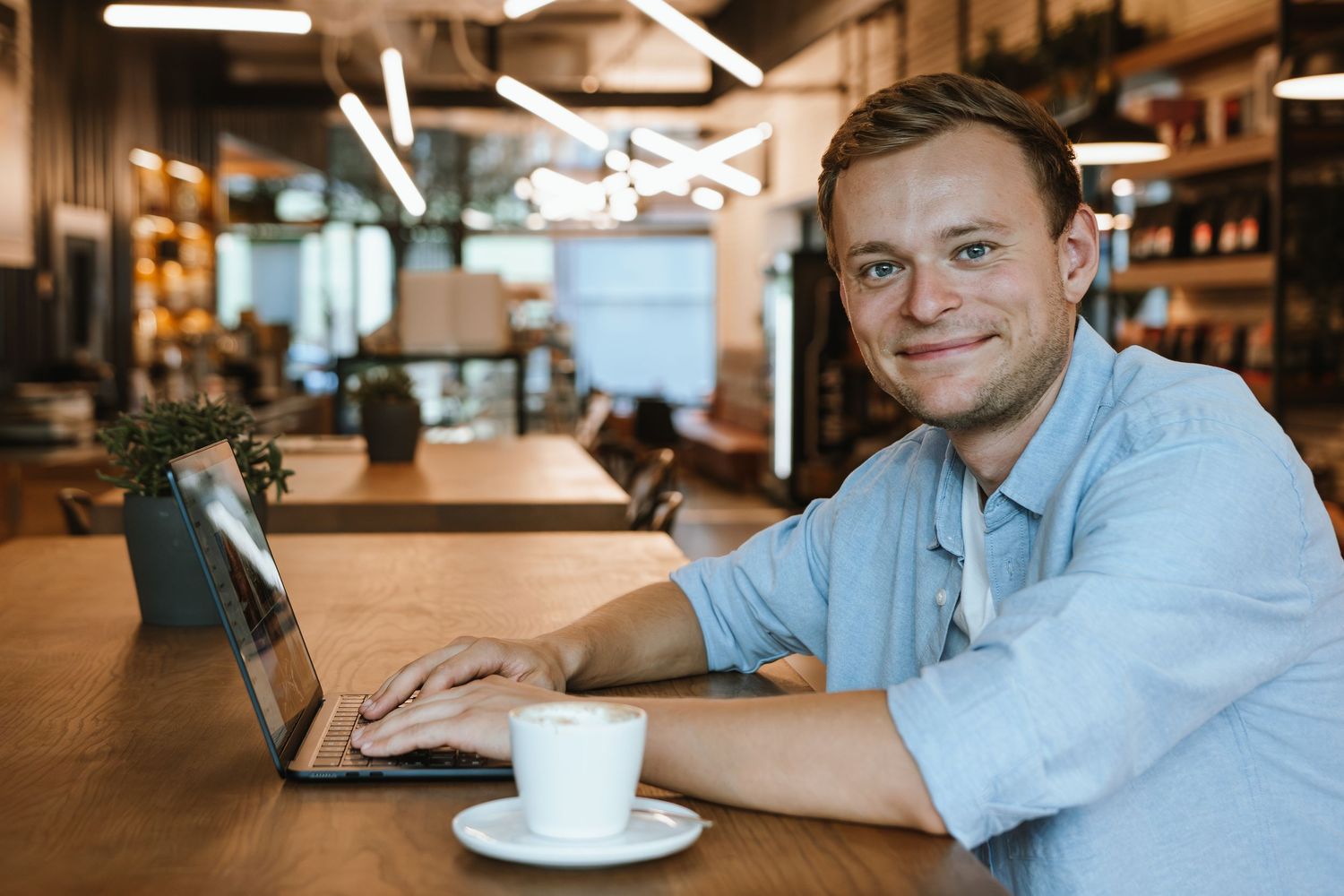 Person working at laptop in casual setting with coffee cup nearby.