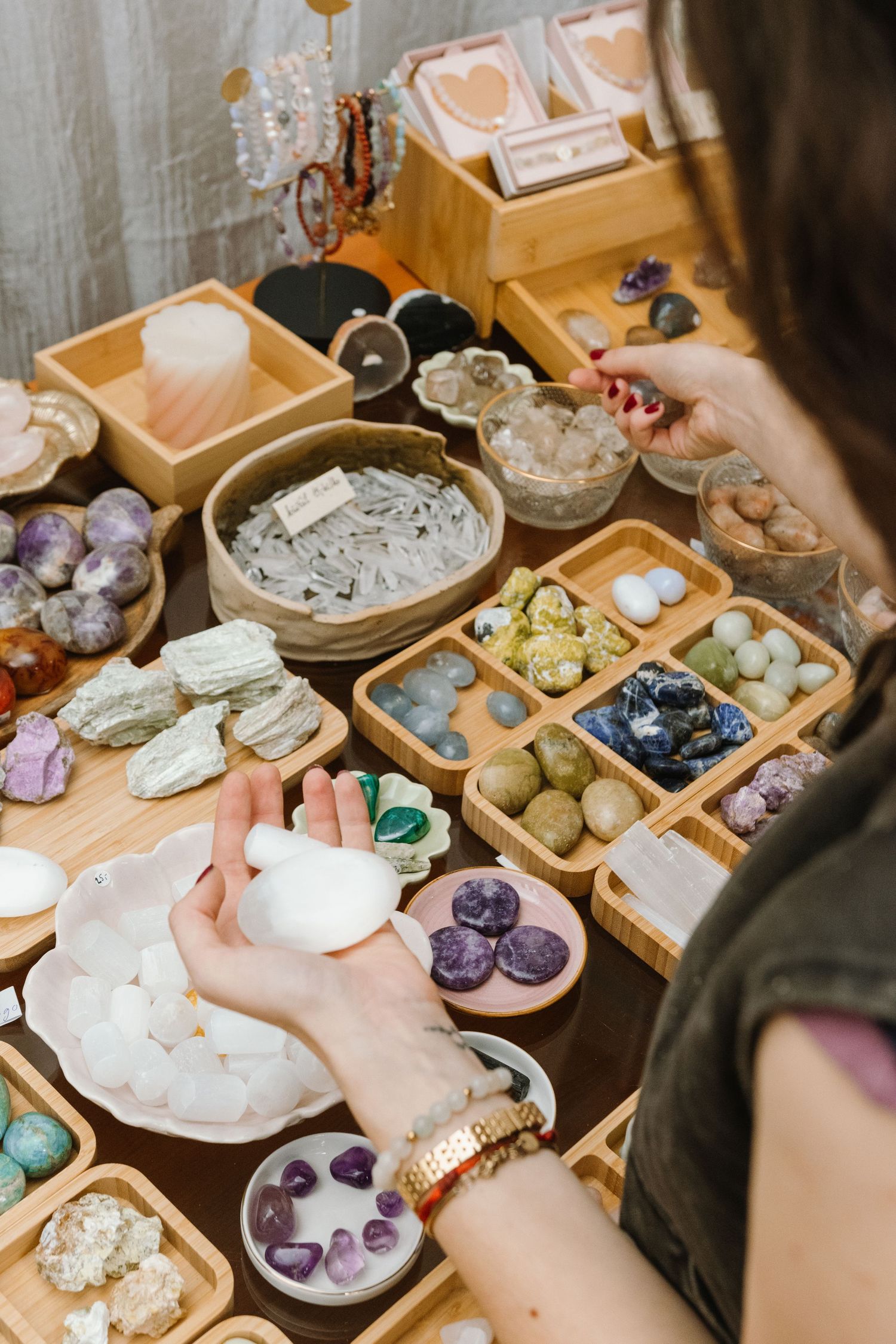Collection of crystals and healing stones displayed in wooden compartment boxes on a table.