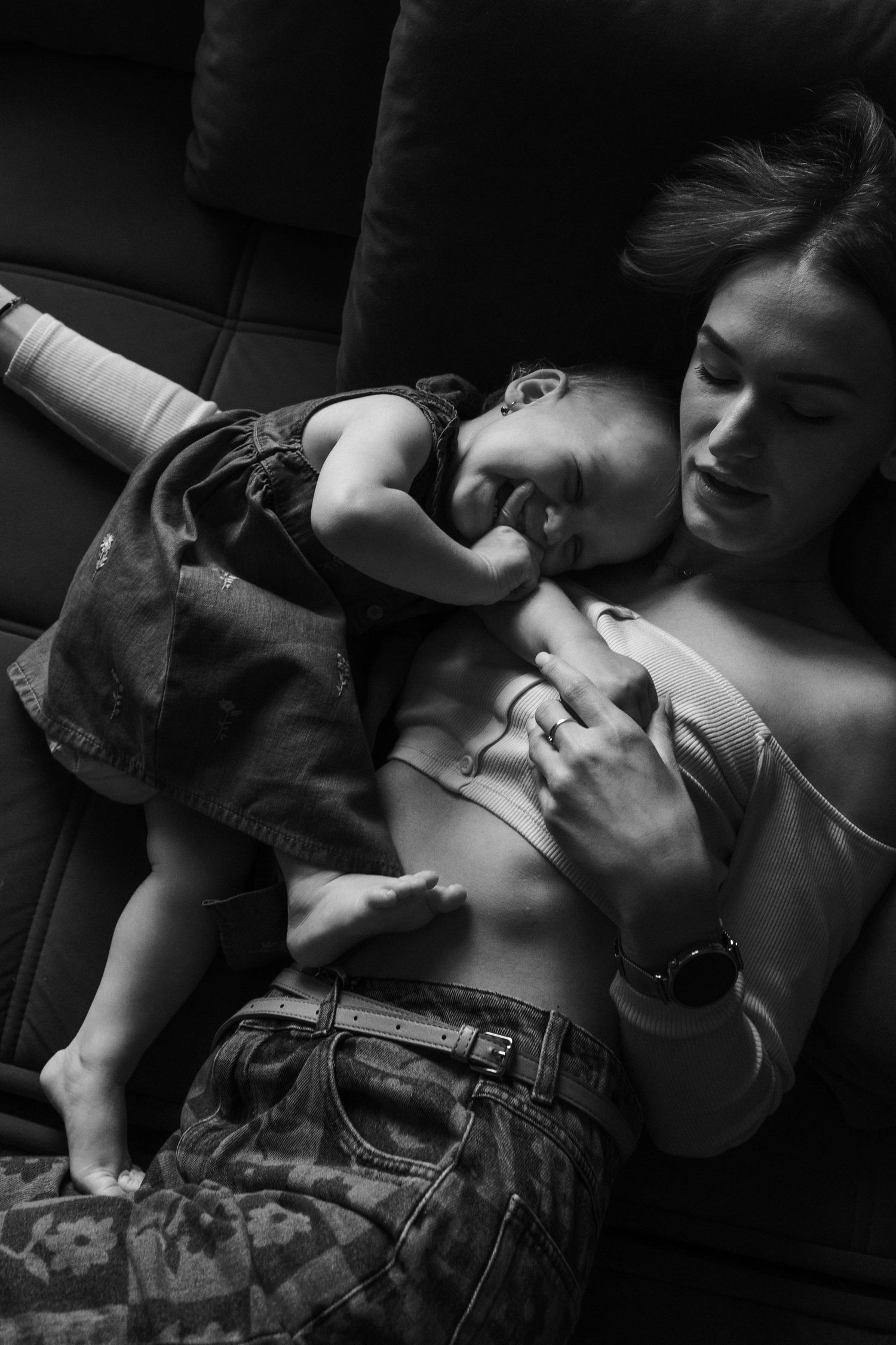 Intimate black and white portrait of parent and baby resting together.