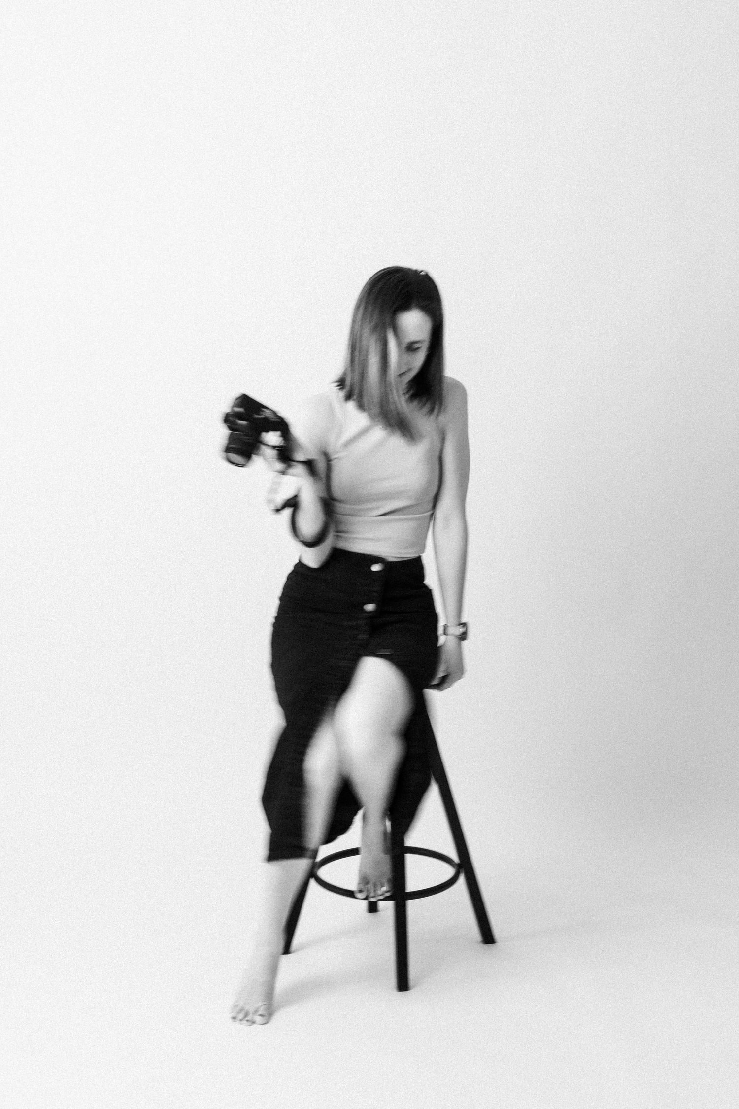 Artistic black and white portrait of photographer on stool with camera.