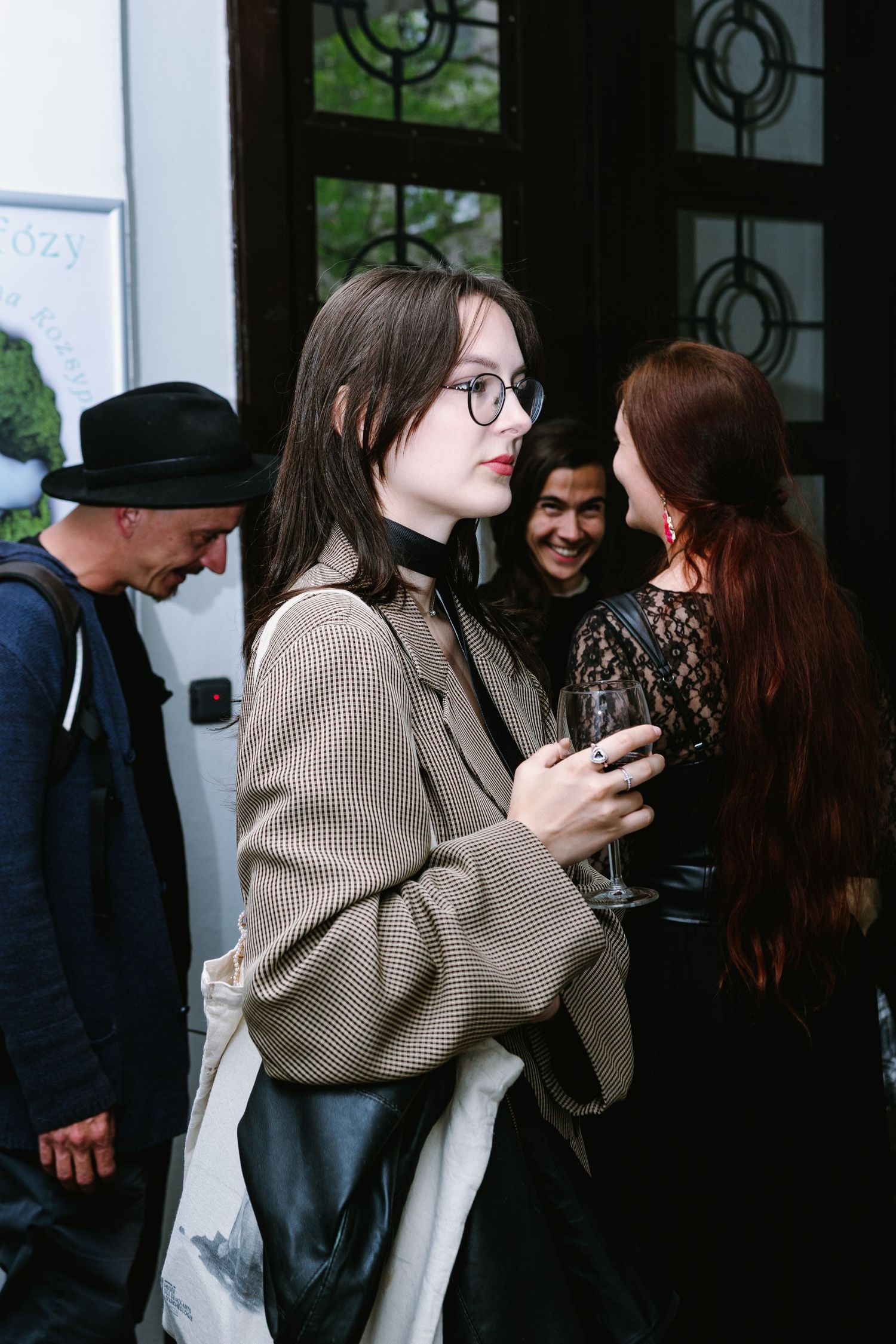 A small group of people gathered by a decorative door having a conversation.
