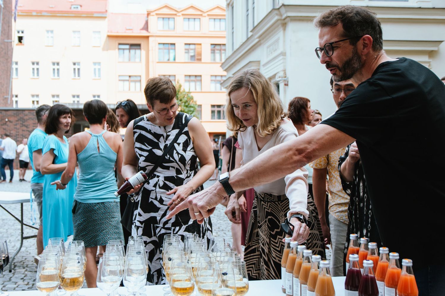 People pouring and serving drinks at an outdoor social gathering.
