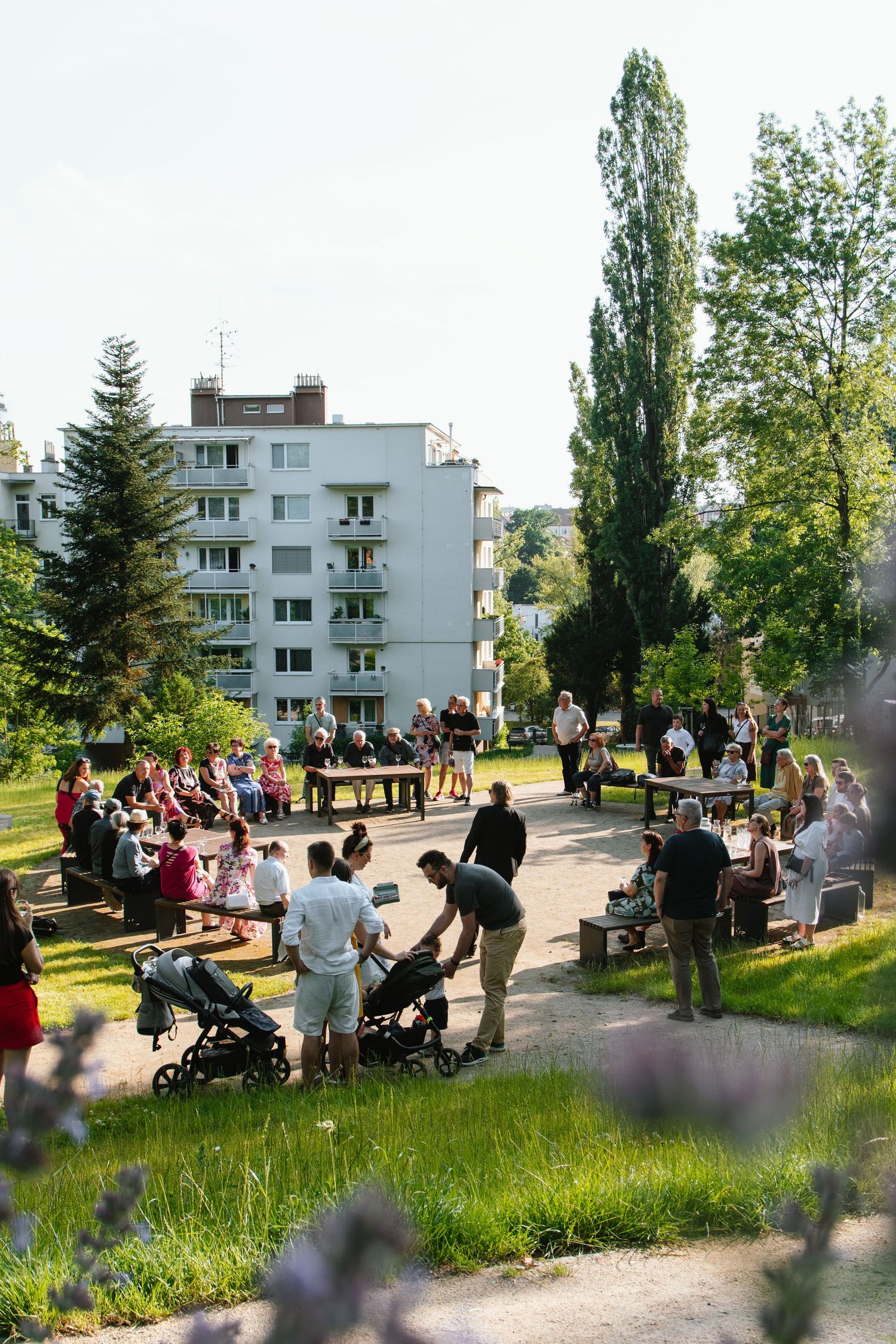 Outdoor social event with people gathered near apartment buildings on a sunny day.