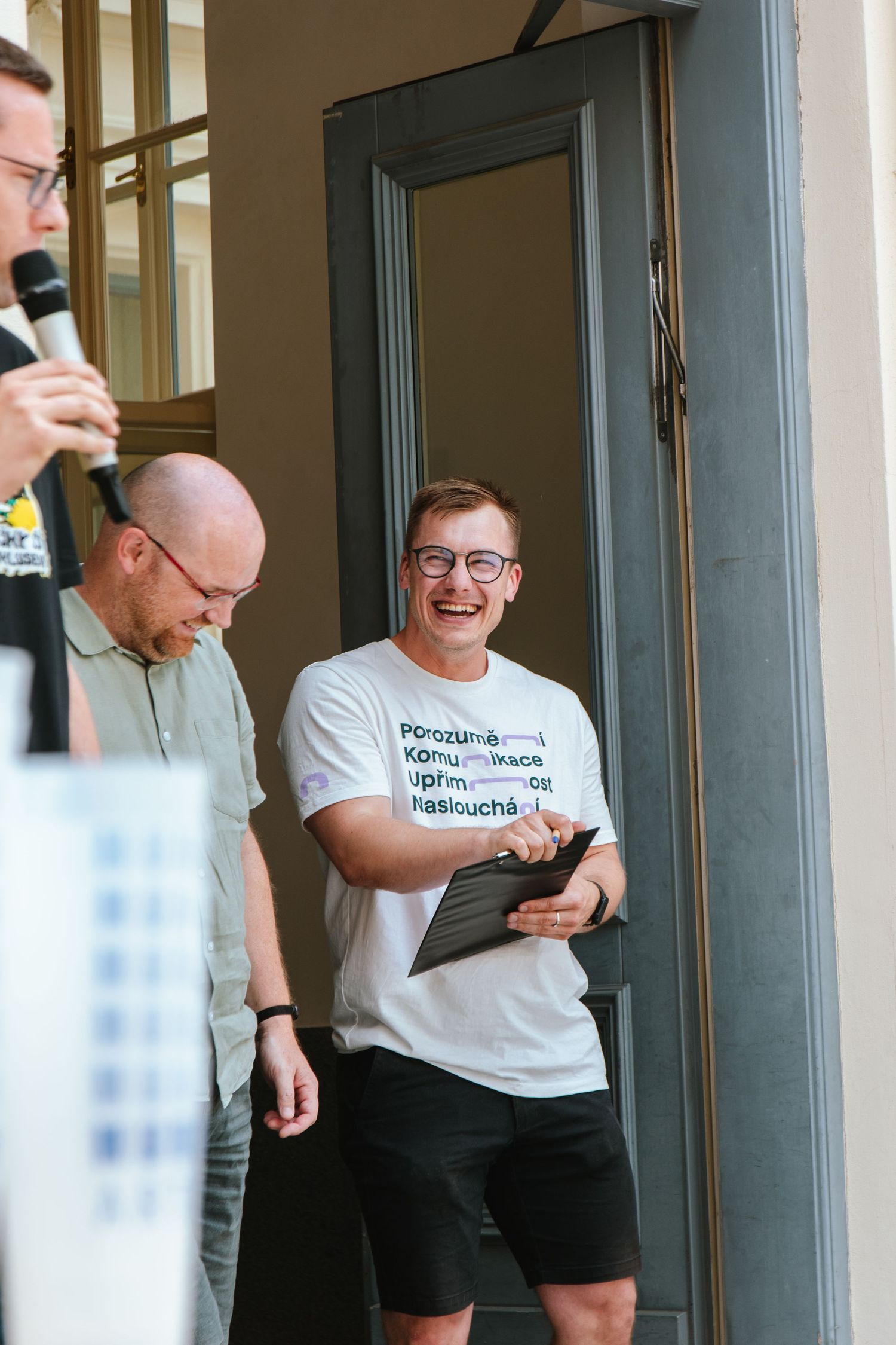 People laughing and chatting in a casual gathering near glass doors.