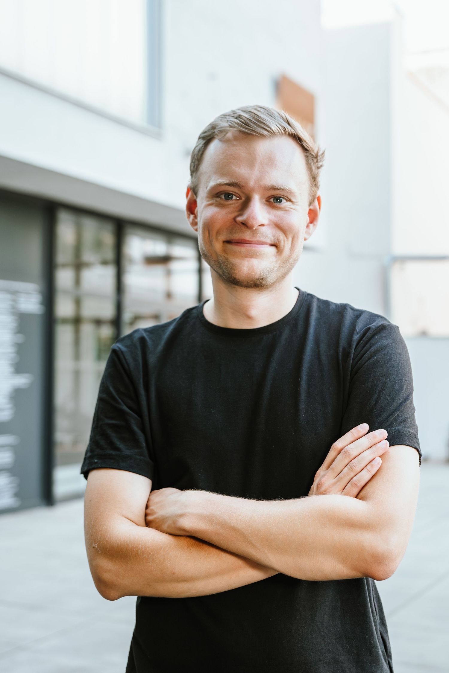 Person in black shirt smiling against bright interior background.