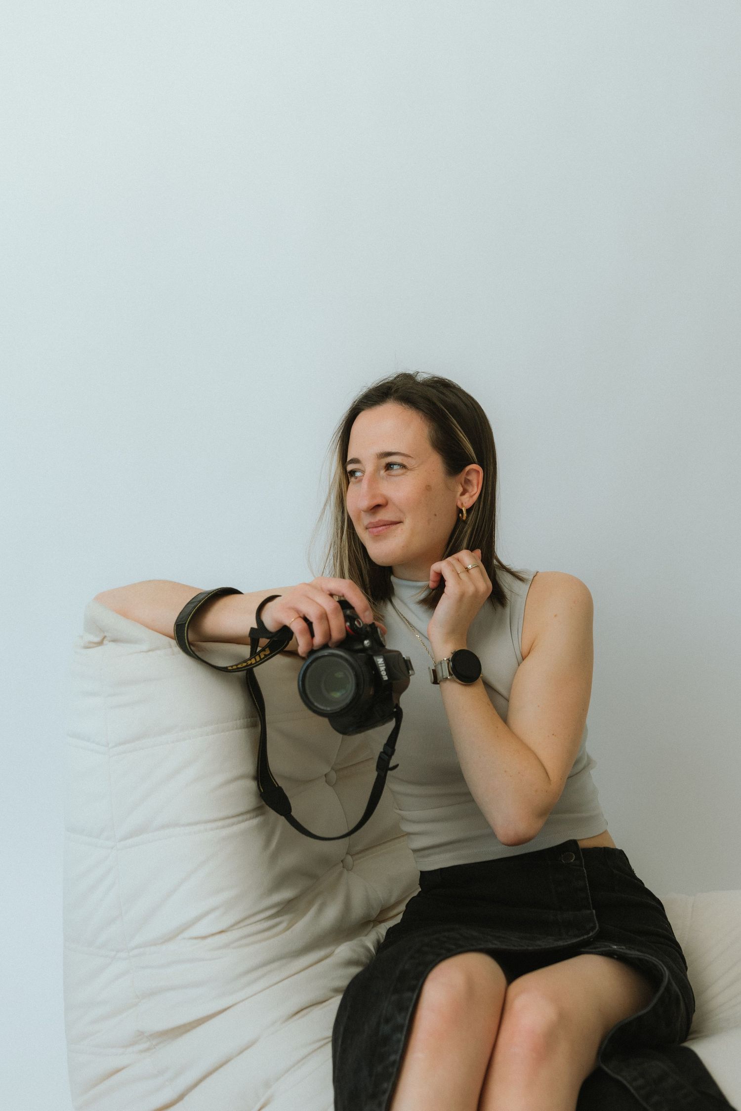 Casual photographer sitting on couch with camera and smartwatch.