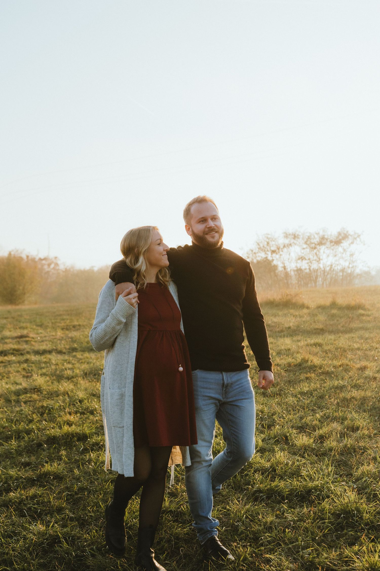 Couple sharing intimate moment in field during golden hour.