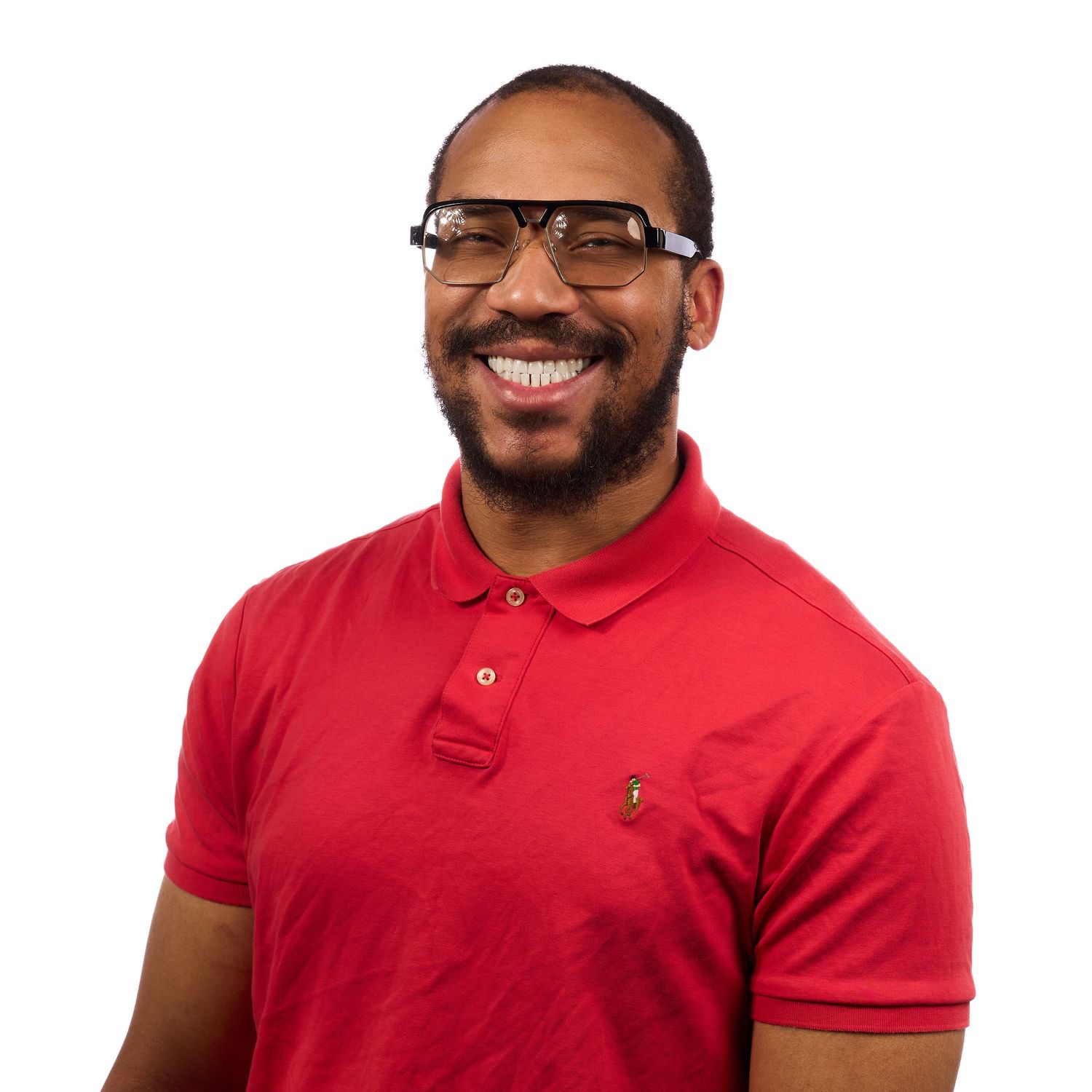 Smiling man with glasses and beard wearing a red polo shirt against a white background.