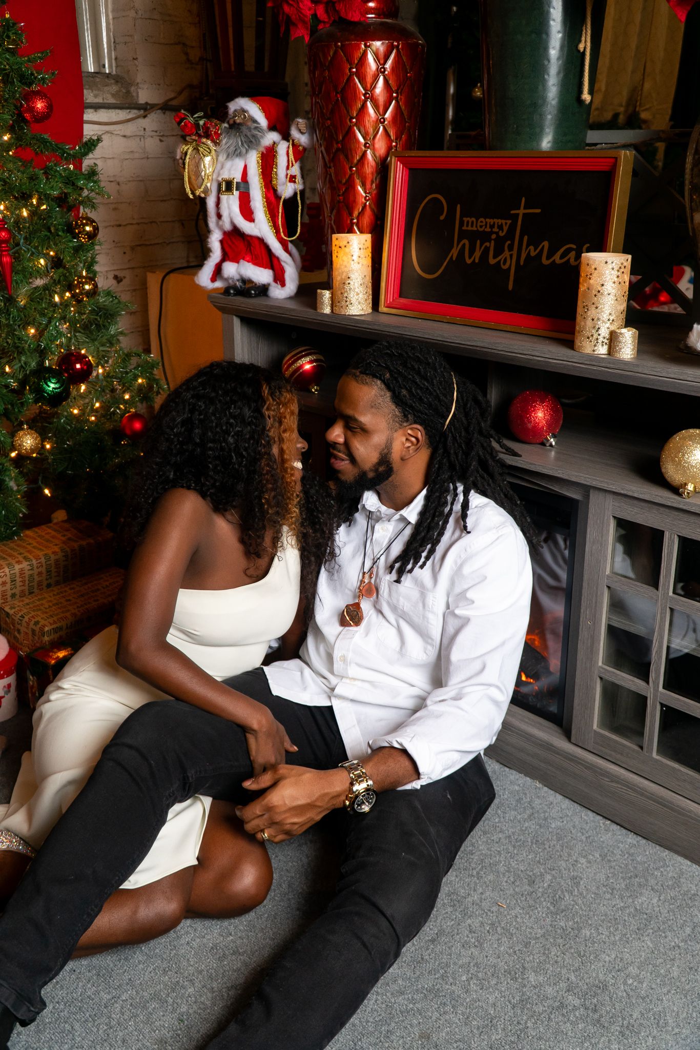 Couple sitting intimately by a fireplace decorated with Christmas candles and holiday decor.