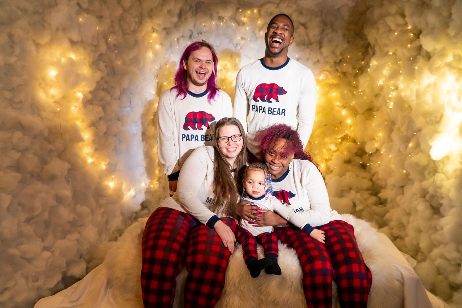 Blended family smiling in matching bear family Christmas pajamas against a glowing backdrop.