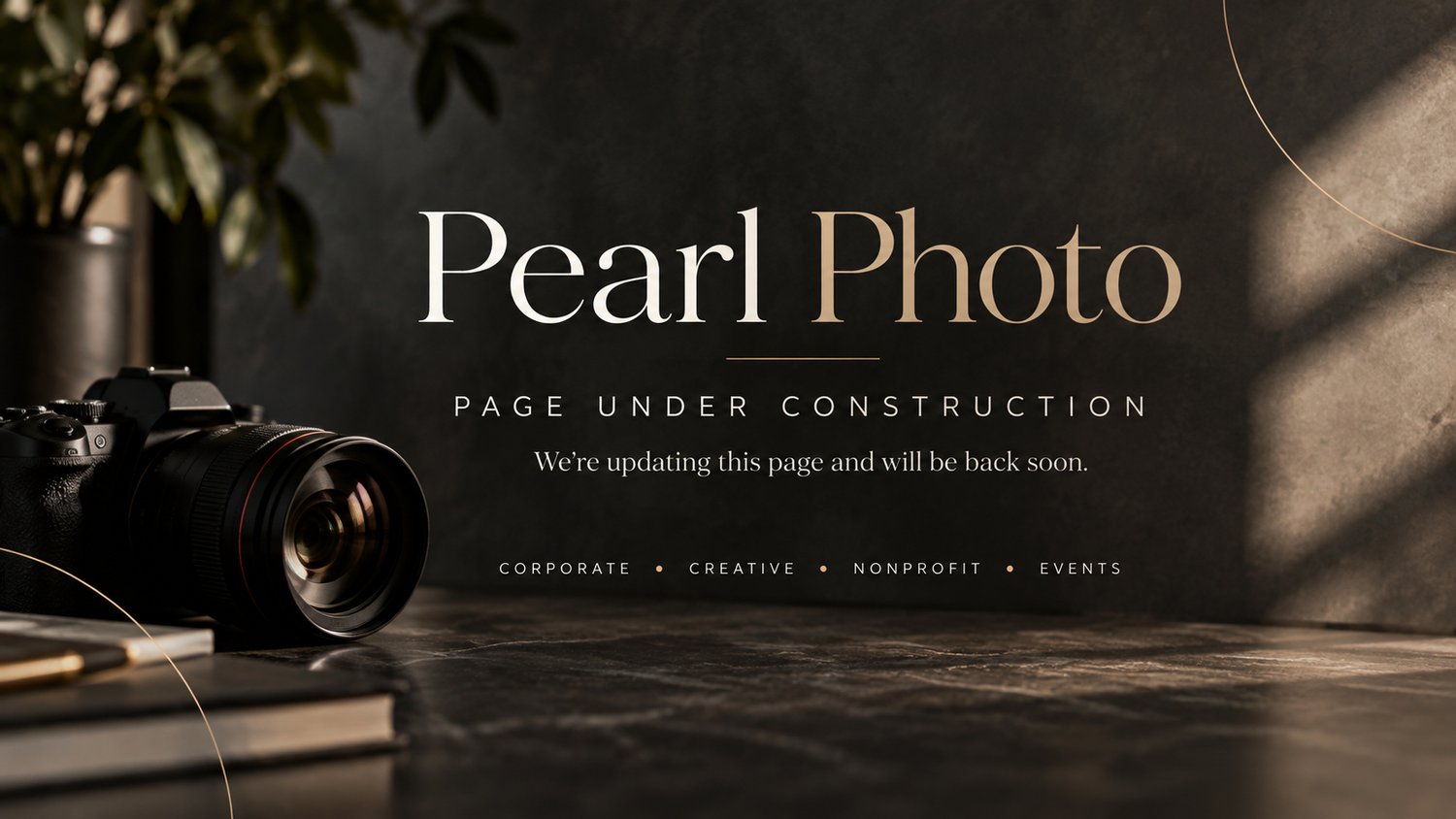 Pearl Photo studio under construction page featuring a DSLR camera on a dark elegant surface with gold typography.