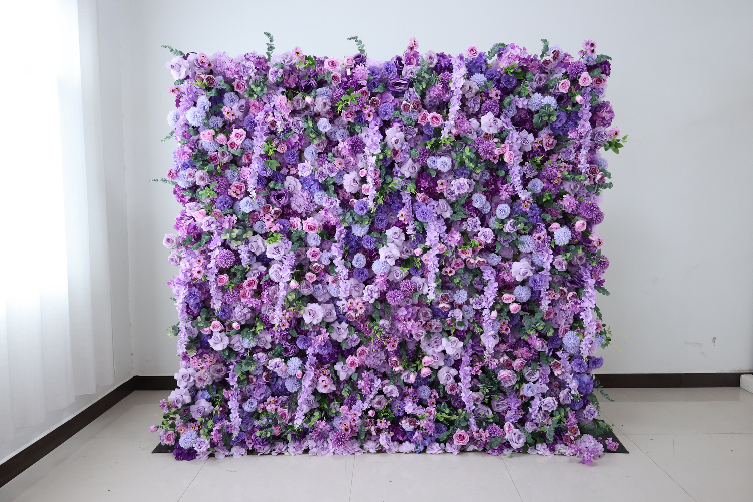 A vibrant purple and lavender flower wall backdrop with mixed blooms for events.