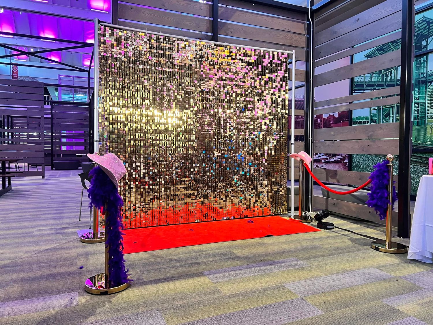 Glamorous gold sequin backdrop with red carpet and velvet rope at an elegant event venue.