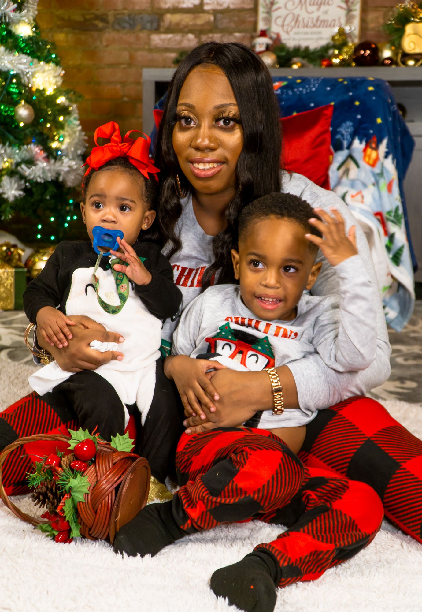 Mother sitting with baby girl and young son in Christmas holiday portrait session.