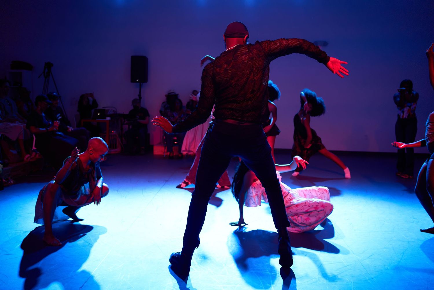 Dancers perform under blue stage lighting during a dynamic contemporary dance performance in a modern venue.