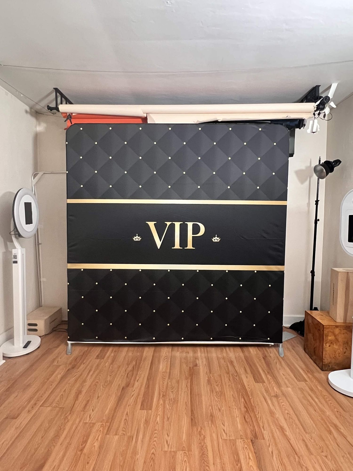 Black quilted VIP photo booth backdrop with gold text and studded details in a photography studio.