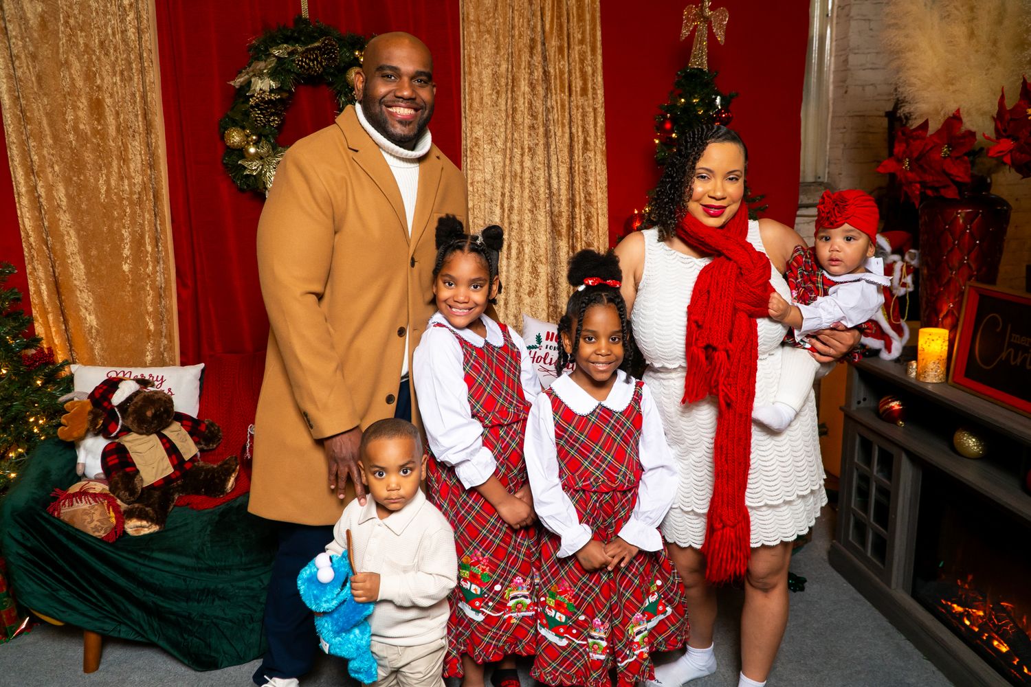 Happy family of six in holiday attire poses together in a festively decorated Christmas setting.