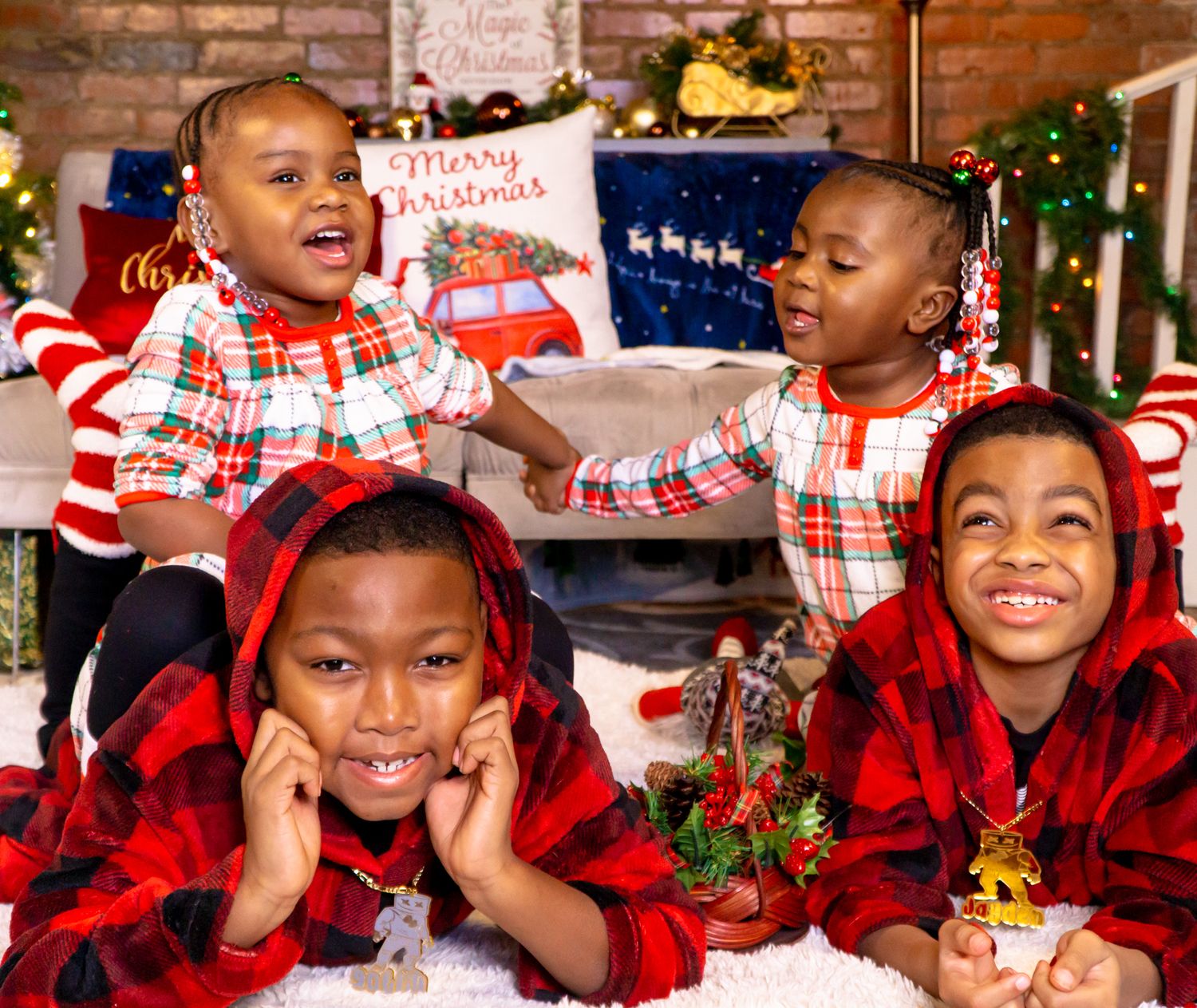 Four young children in red plaid pajamas smiling in festive Christmas portrait.