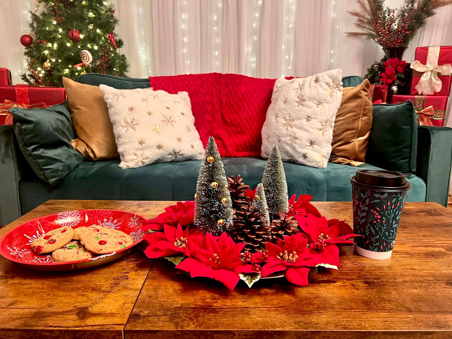 A festive living room coffee table with cookies, poinsettias, and mini Christmas trees on display.