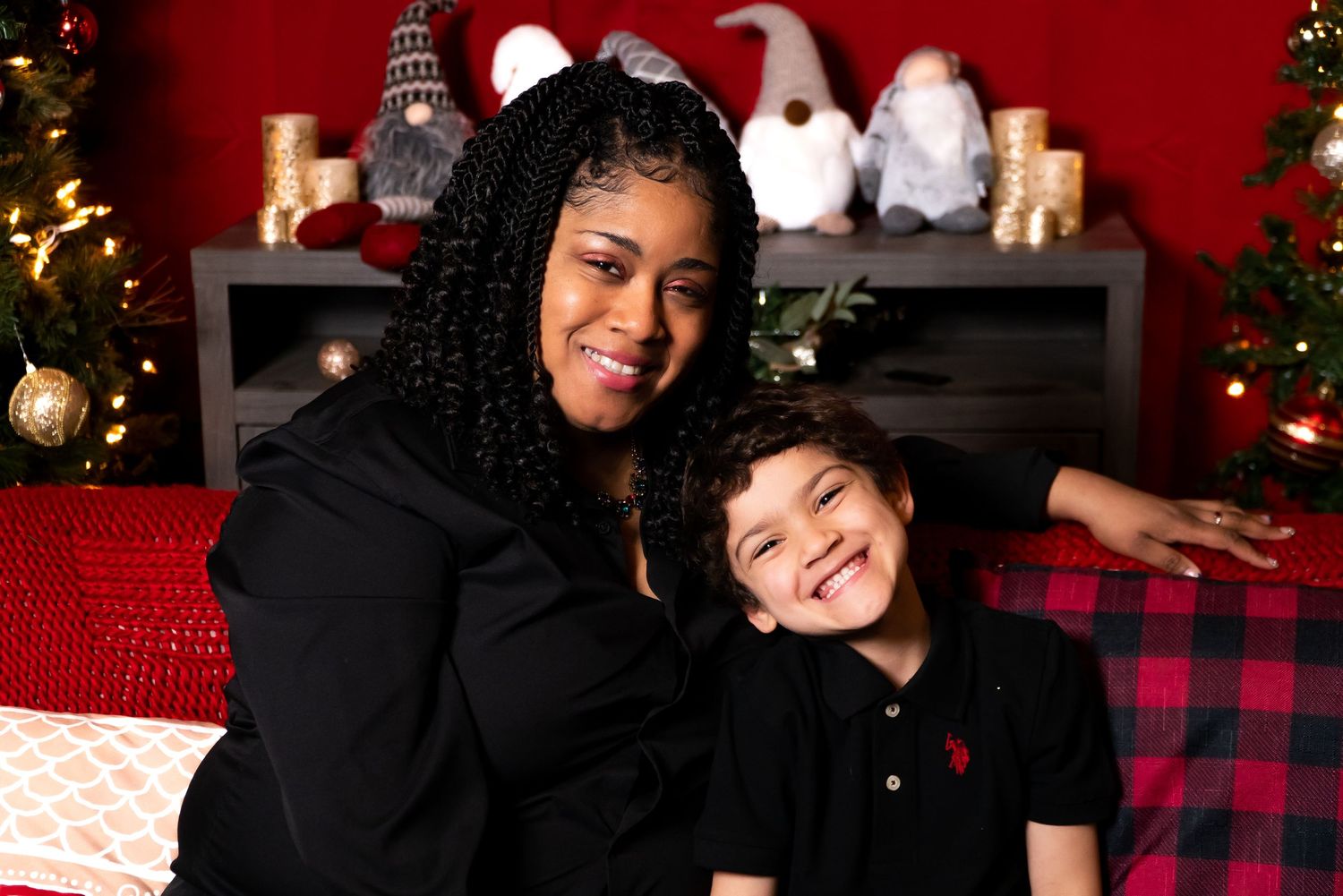 Woman and young boy smiling together in front of Christmas tree holiday photo session.