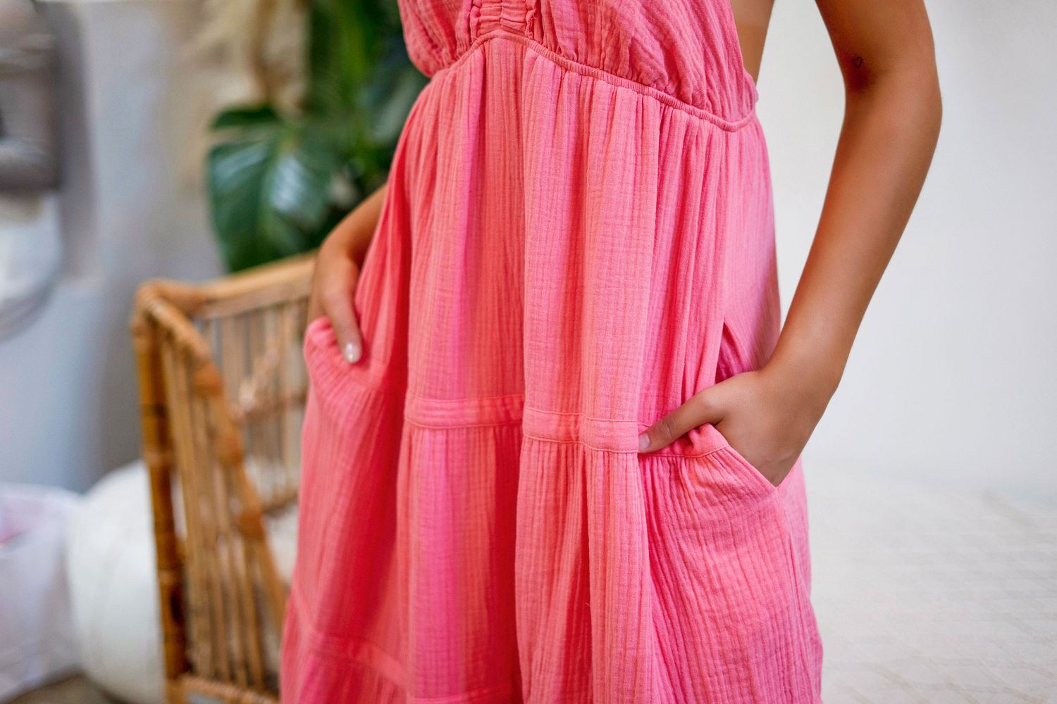 Close-up detail of a pink textured cotton dress with side pockets and gathered waist design.
