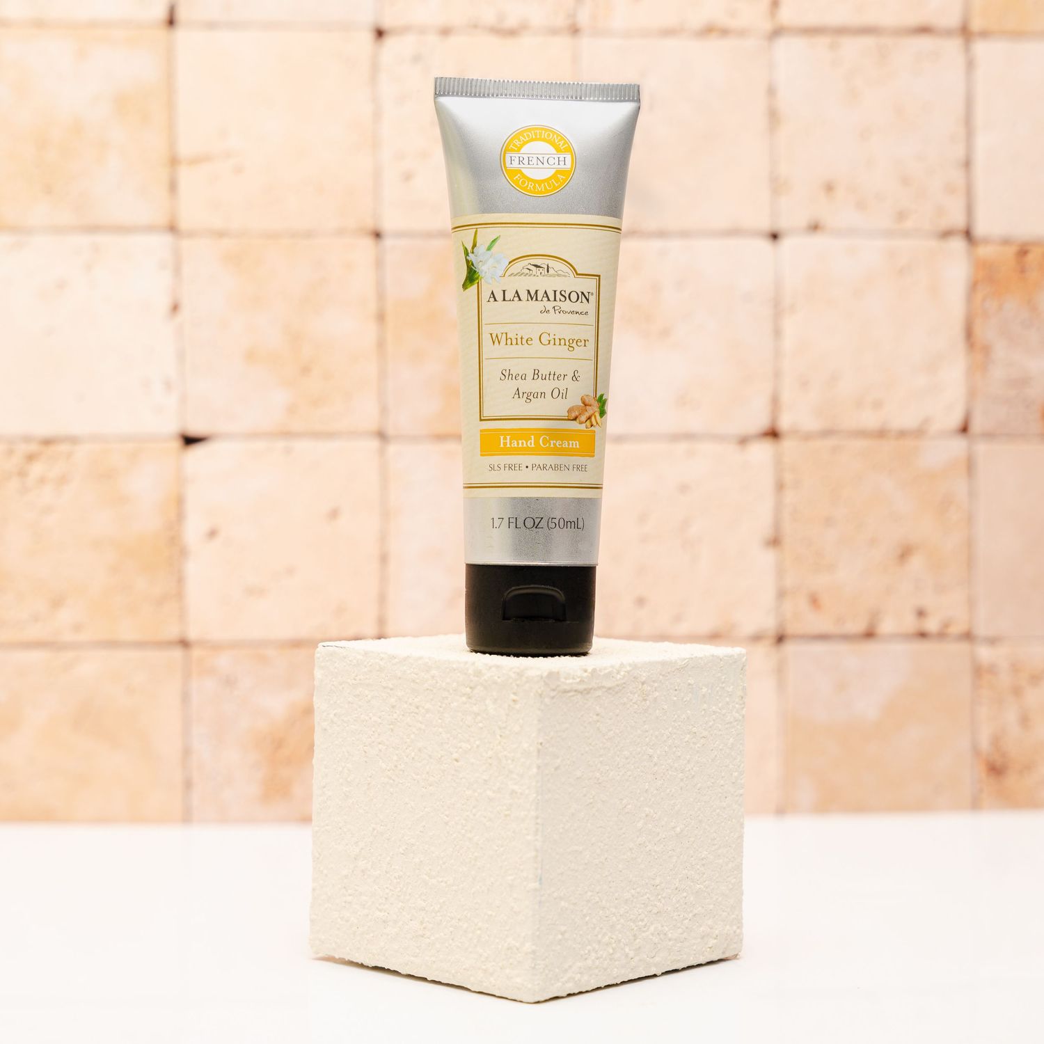 A tube of Salvatore hand cream displayed on a white cube pedestal against a textured beige background.