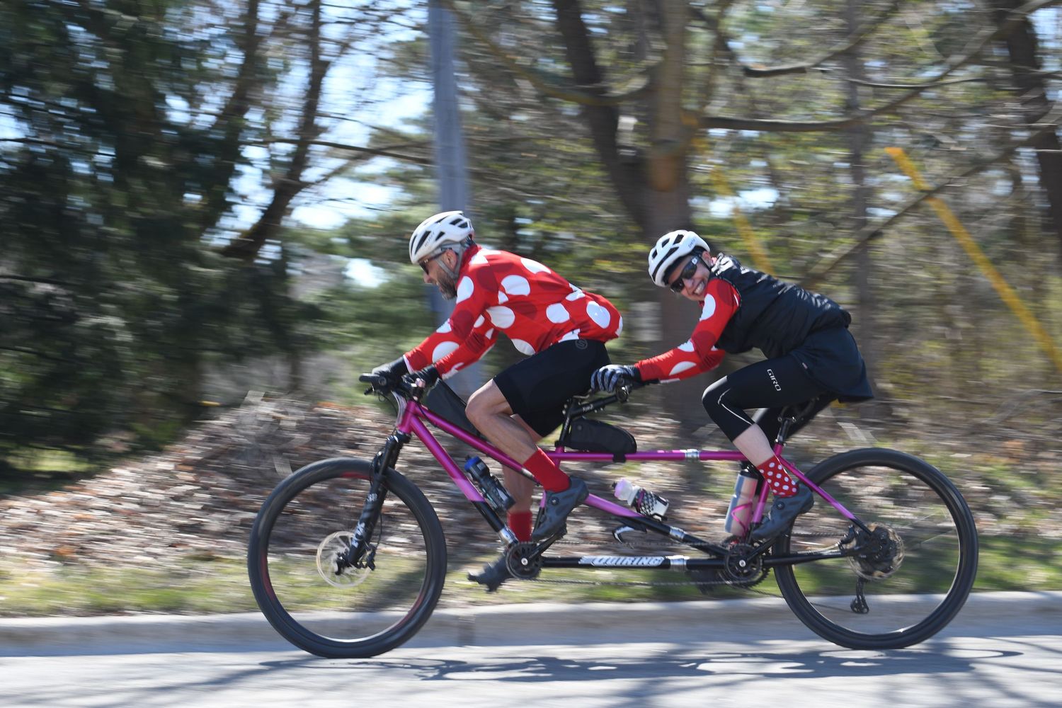 Tandem cyclists pedaling together on a forested road during outdoor ride