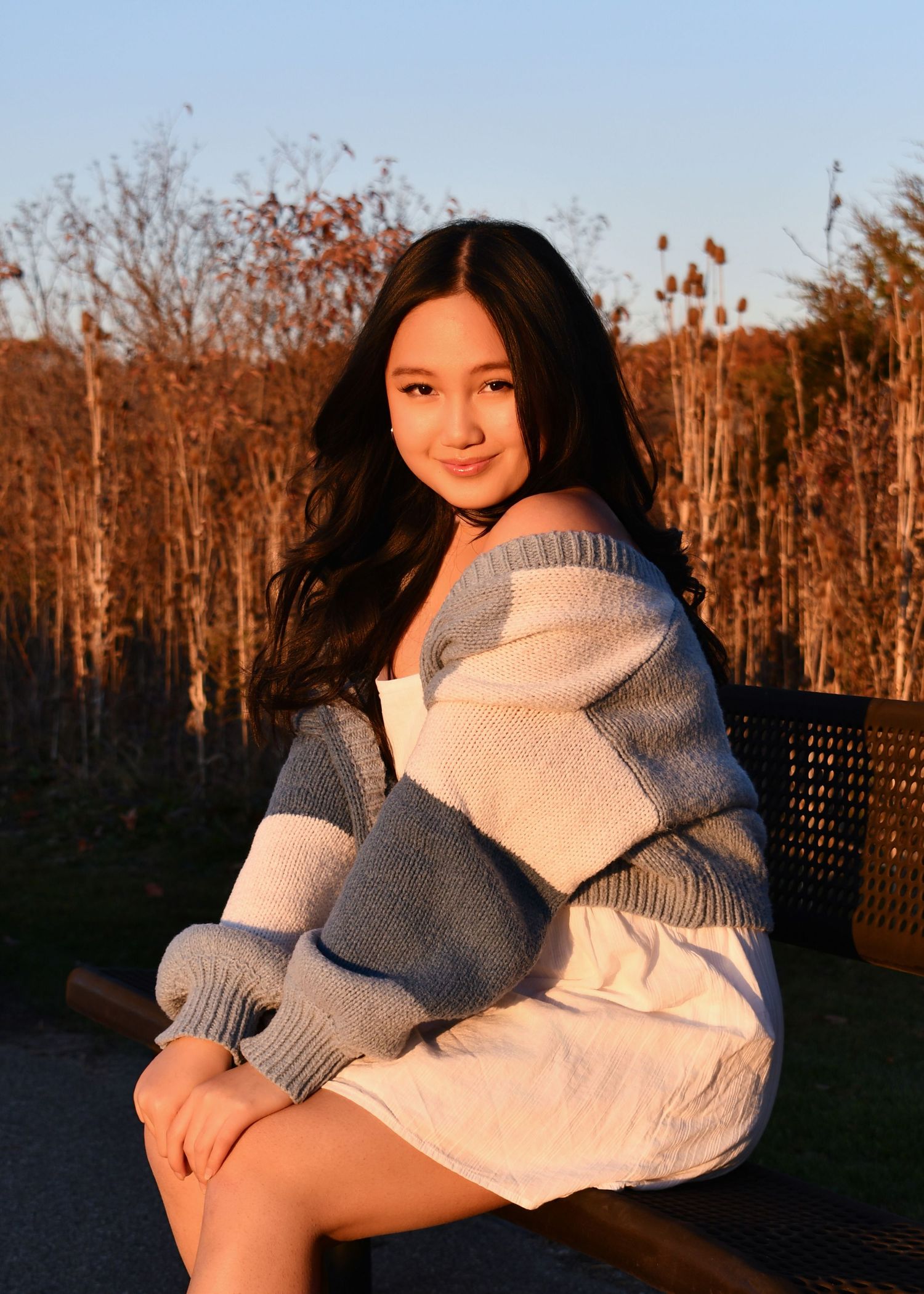 Warm, natural senior portrait on bench during golden hour