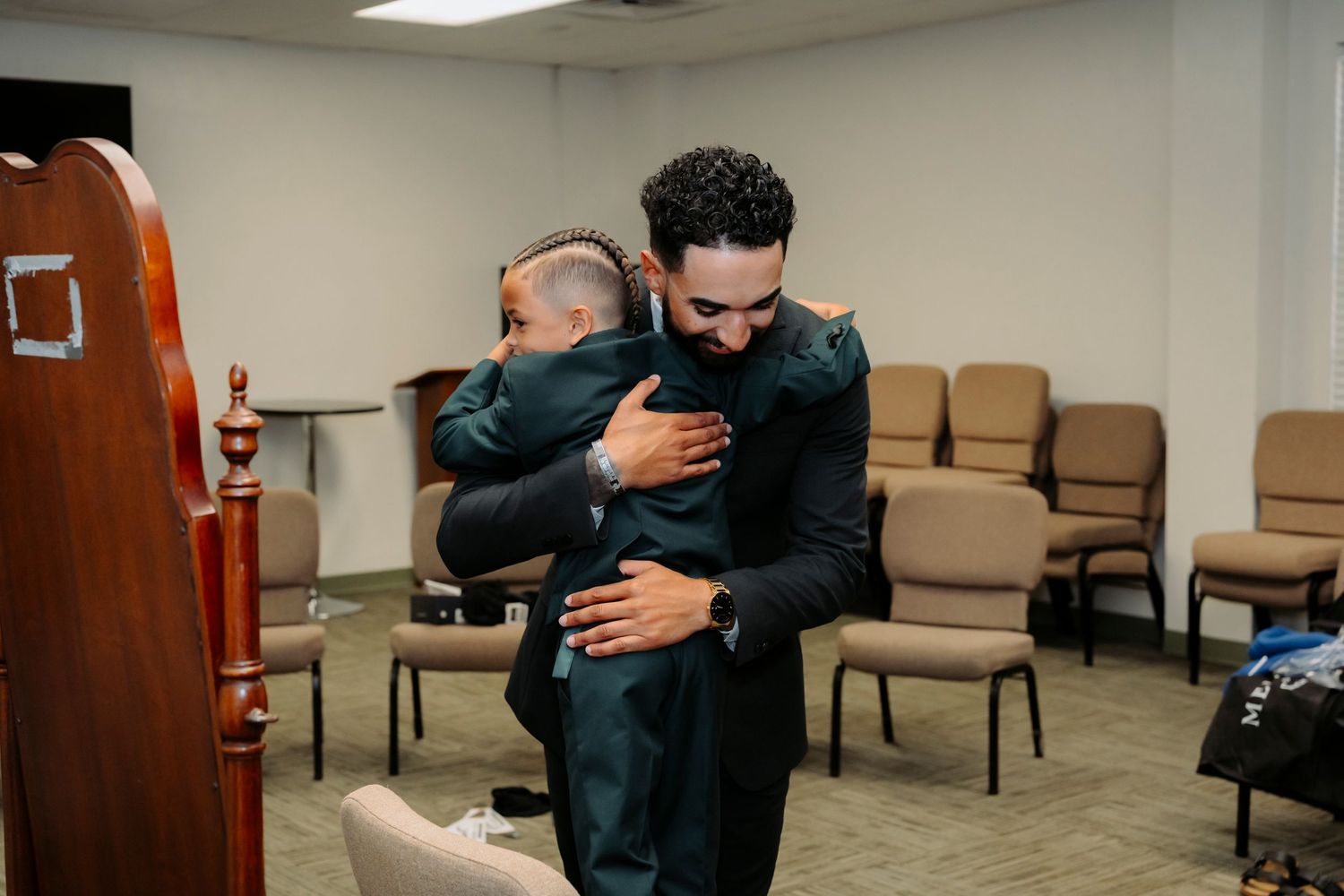 People sharing heartfelt hugs in a room with chairs.