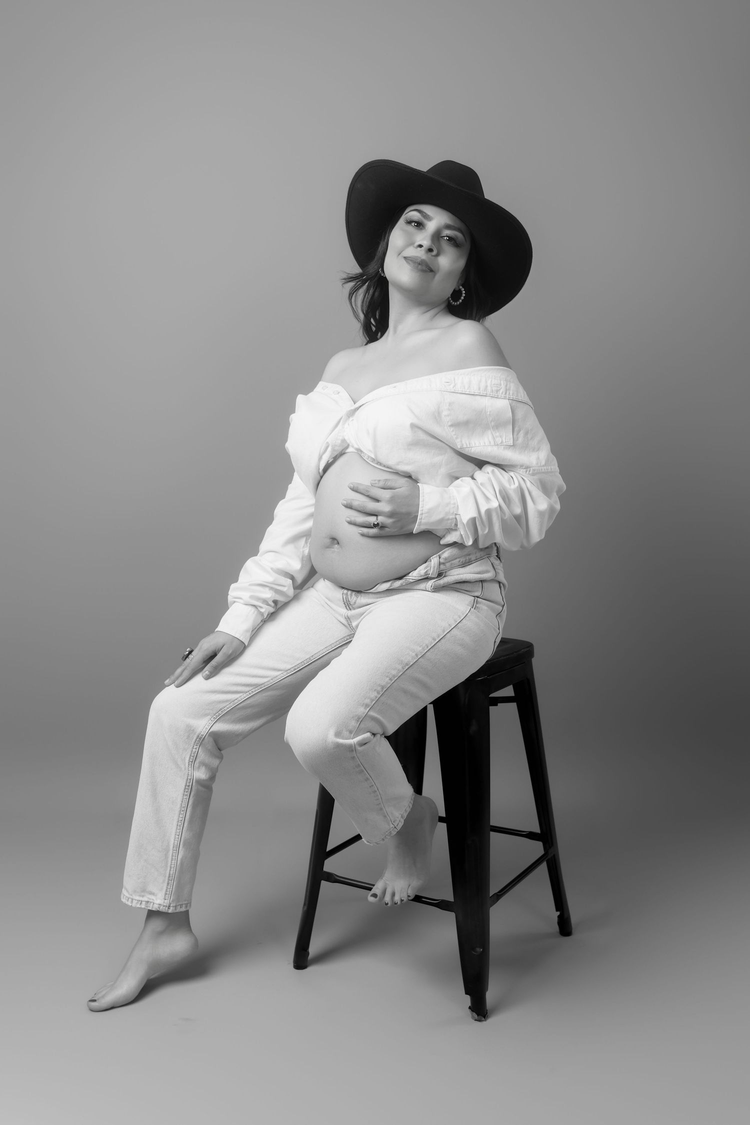 Elegant maternity photos combining white attire and a black hat in various posed positions.