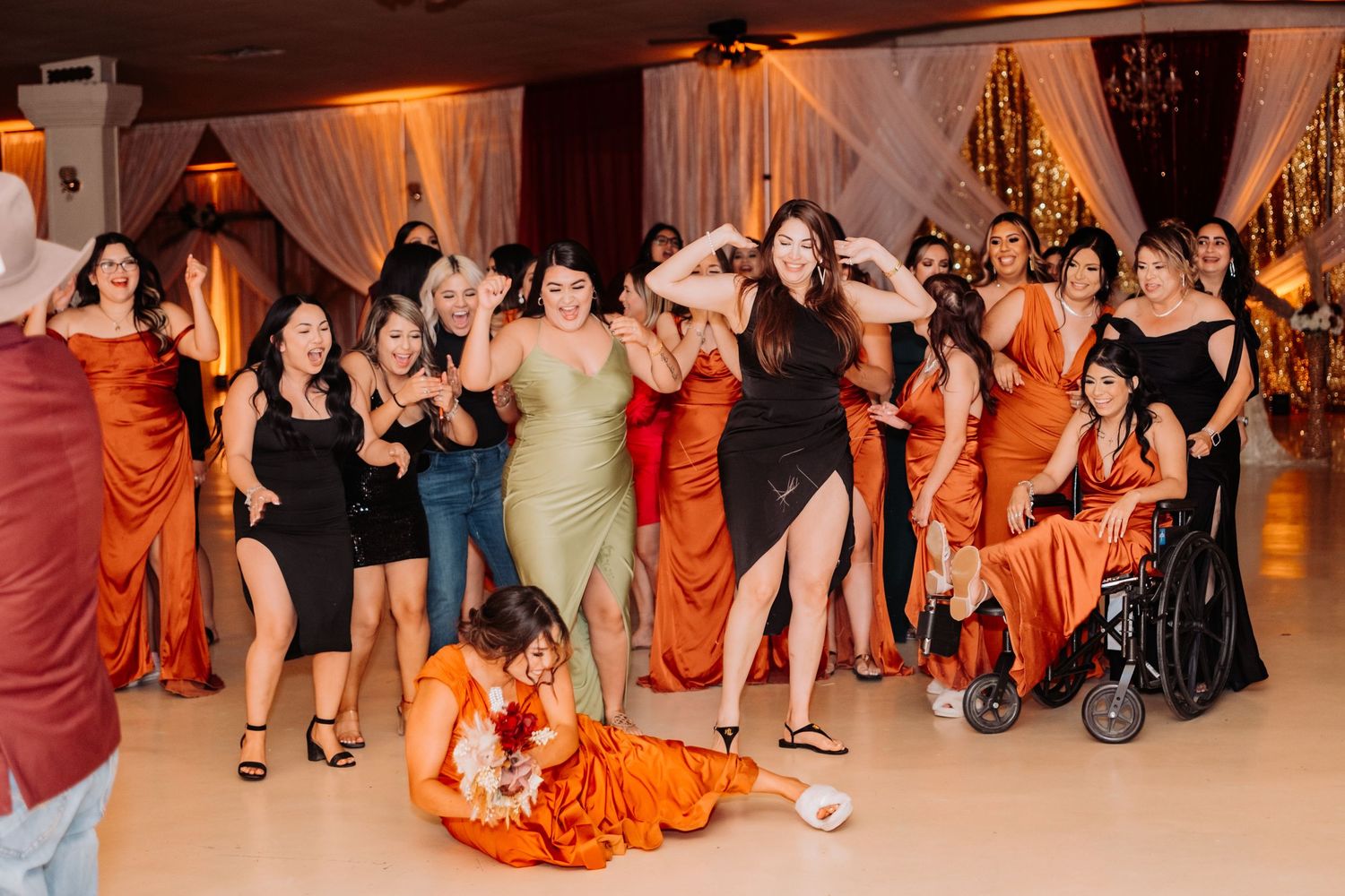 Wedding guests performing choreographed dance moves on reception dance floor.
