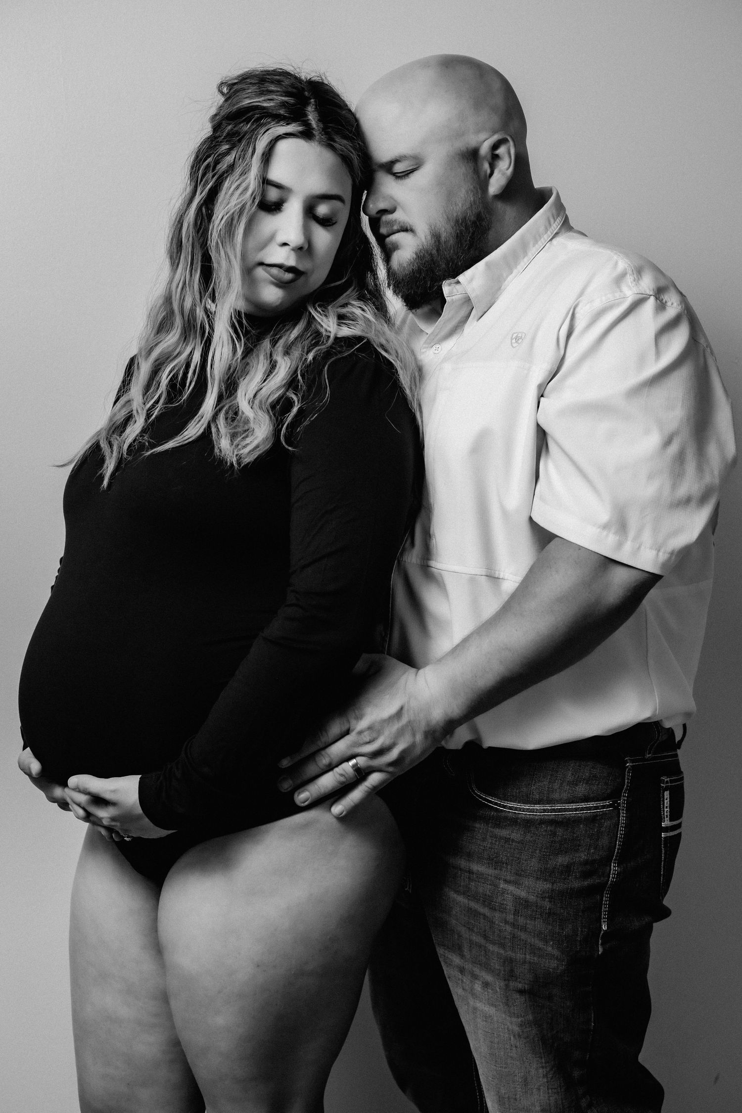 Intimate black and white maternity photo of couple in studio setting.