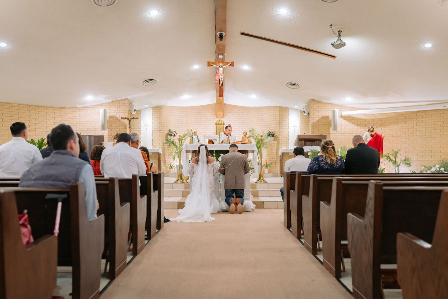 Wedding ceremony in progress inside traditional church with wooden pews.
