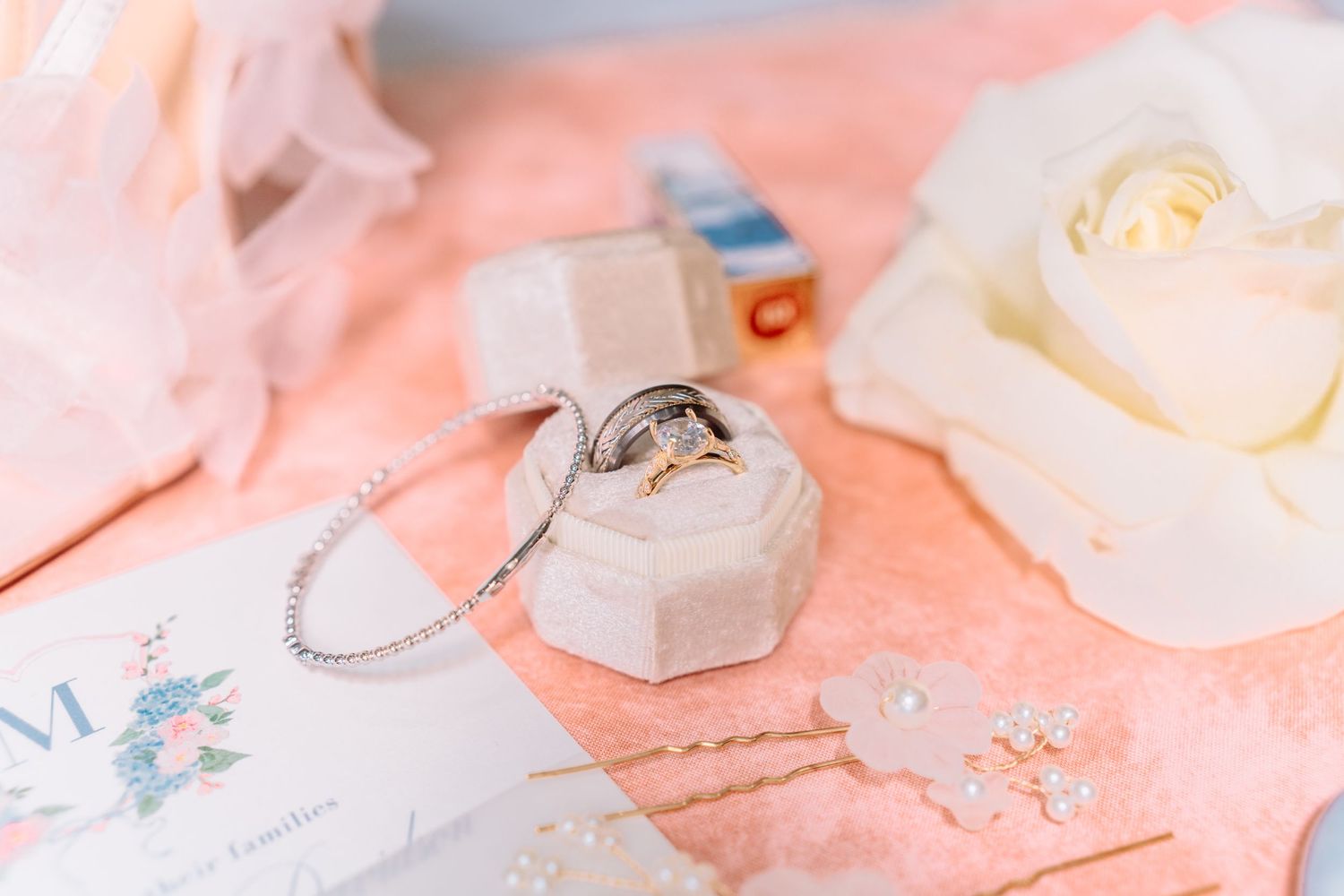 Wedding rings displayed on a hexagonal ring box with delicate pink floral details.